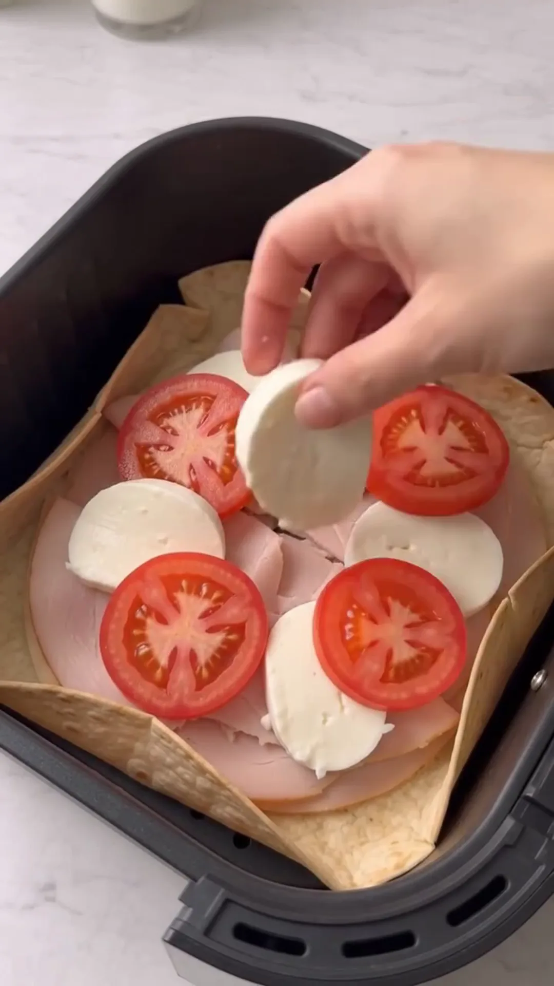 Air Fryer Smoked Turkey, Tomato & Mozzarella Tortilla – placing ingredients in an air fryer basket