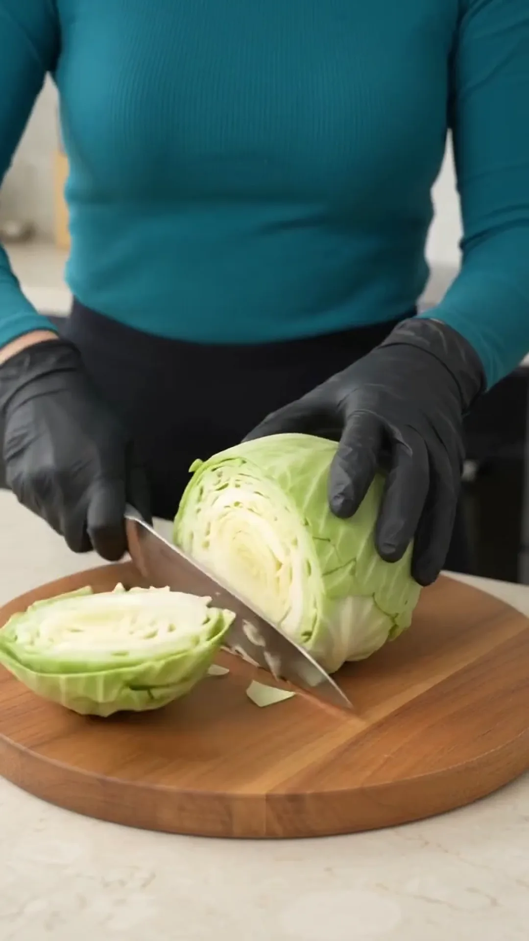 Baked Cabbage Steaks with Ground Beef, Tomato and Cheese – A person is cutting a head of cabbage on a wooden cutting board