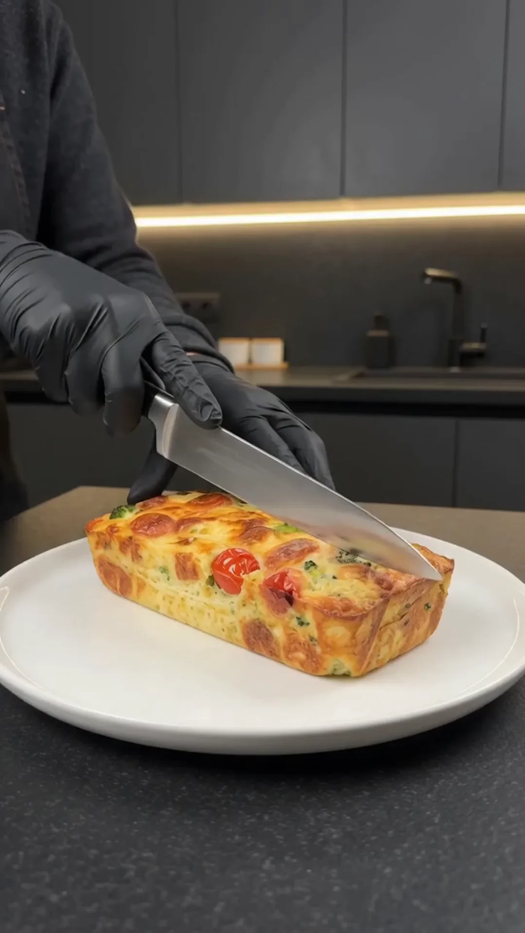 Cheesy Broccoli Meat Stacks with Roasted Cauliflower – A person is cutting a rectangular frittata on a plate