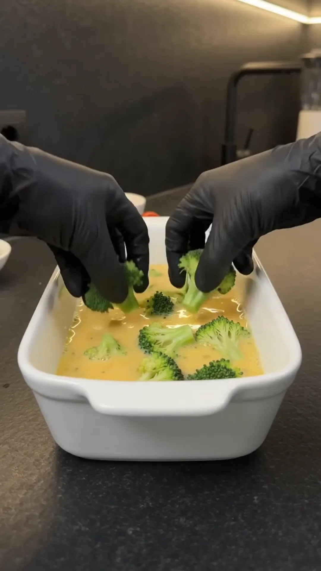 Cheesy Broccoli Meat Stacks with Roasted Cauliflower – person is preparing broccoli in a dish