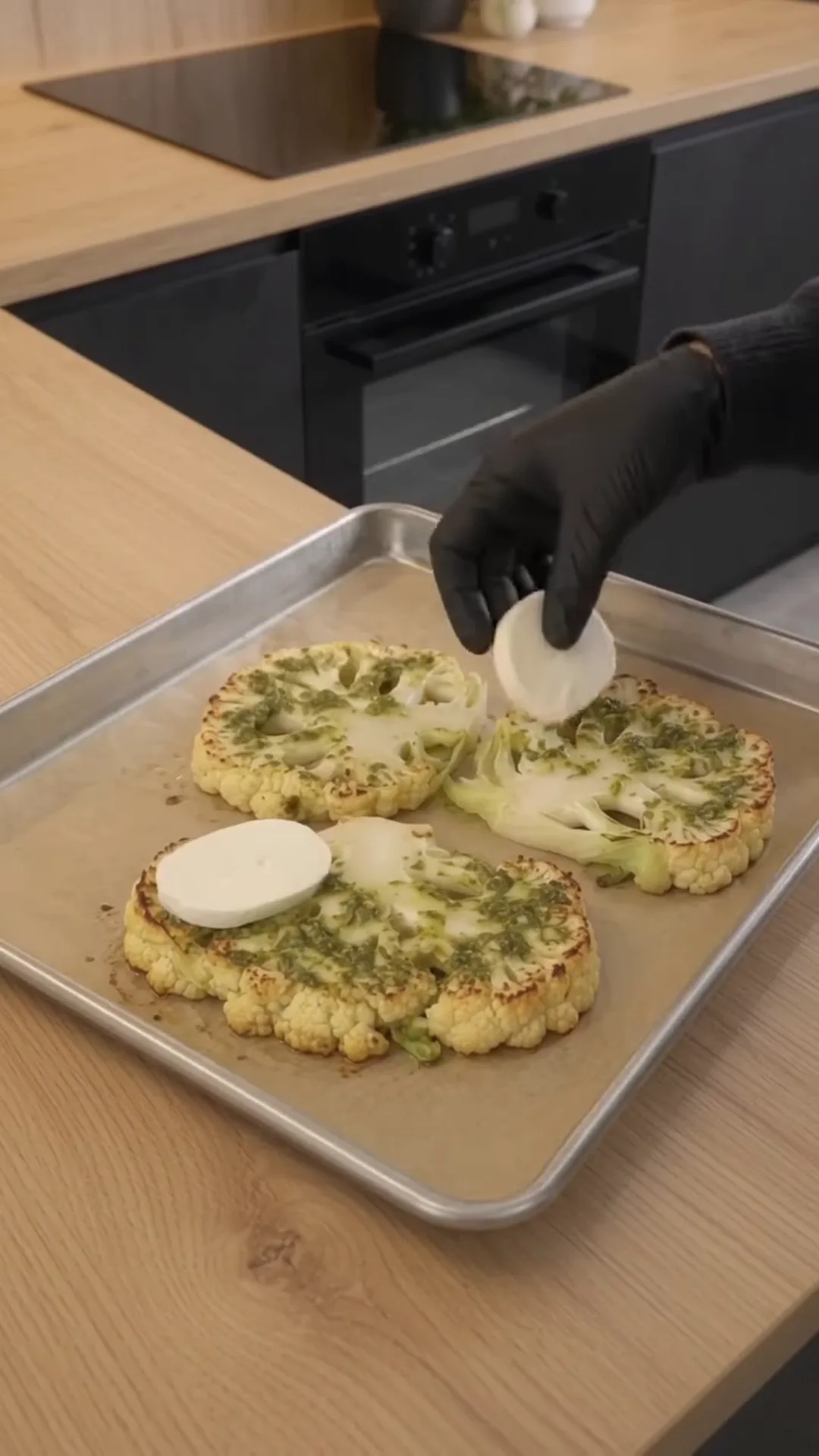 Cheesy Pesto Caprese Cauliflower Steaks – person placing cauliflower steaks on a baking tray