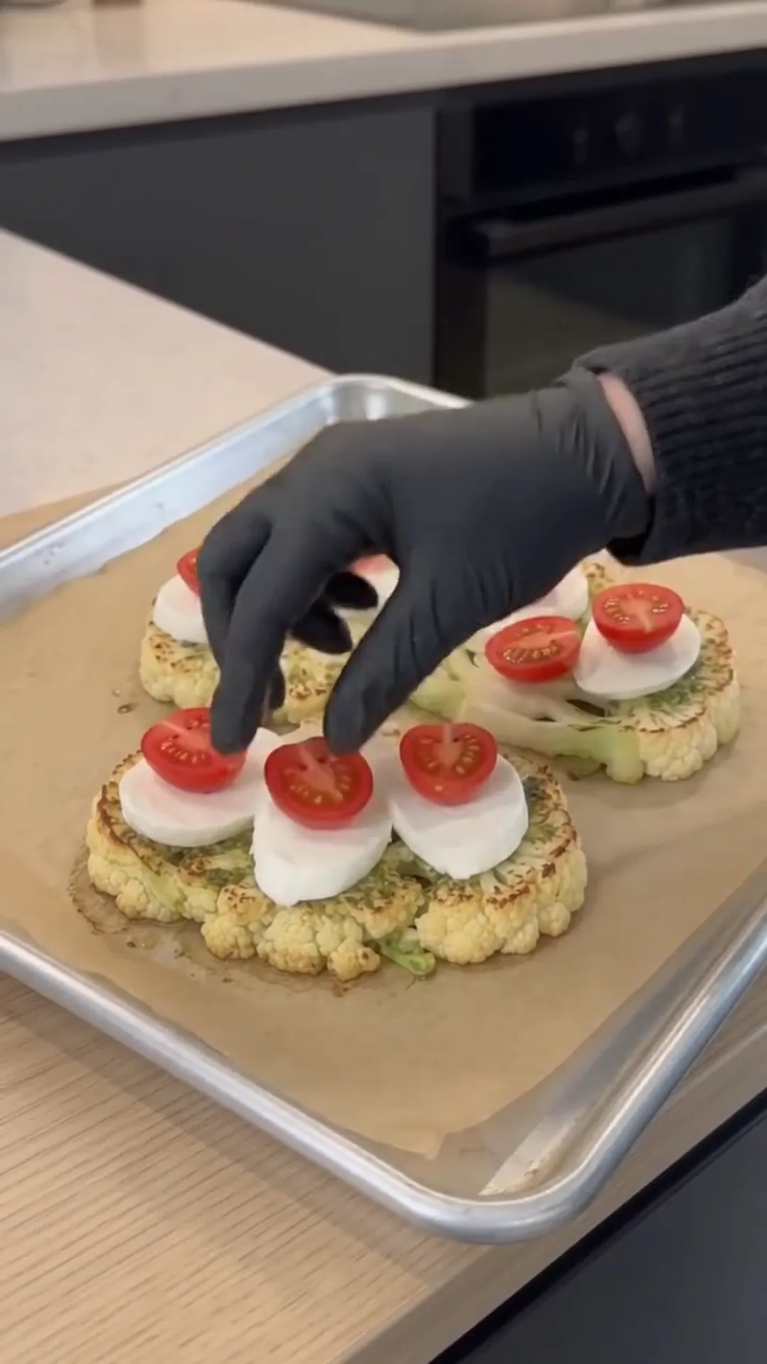 Cheesy Pesto Caprese Cauliflower Steaks – placing toppings on roasted cauliflower steaks