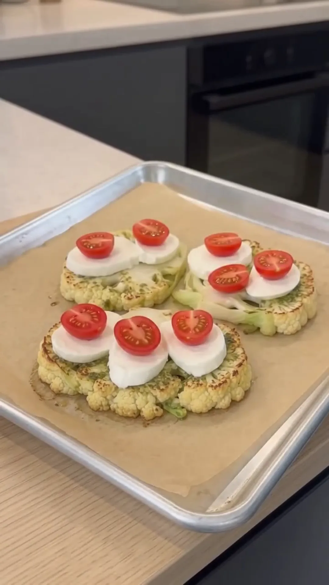 Cheesy Pesto Caprese Cauliflower Steaks – placing sliced vegetables on a baking tray