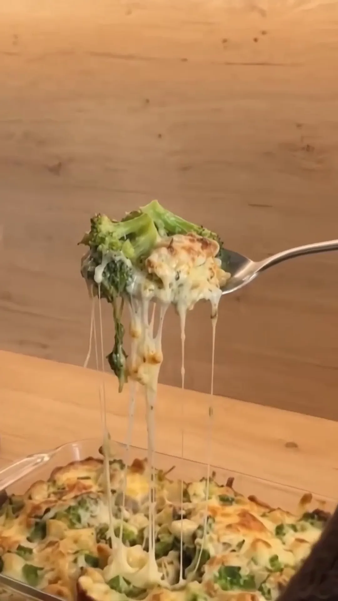 Creamy Low-Carb Chicken and Broccoli Alfredo Casserole – A fork is lifting a cheesy broccoli casserole from a baking dish