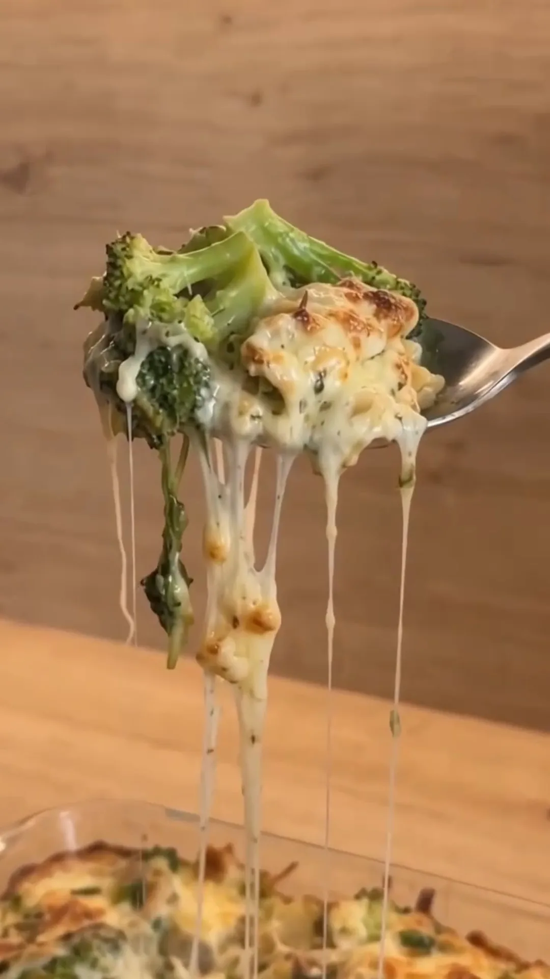 Creamy Low-Carb Chicken and Broccoli Alfredo Casserole – A fork is lifting a cheesy broccoli casserole from a baking dish