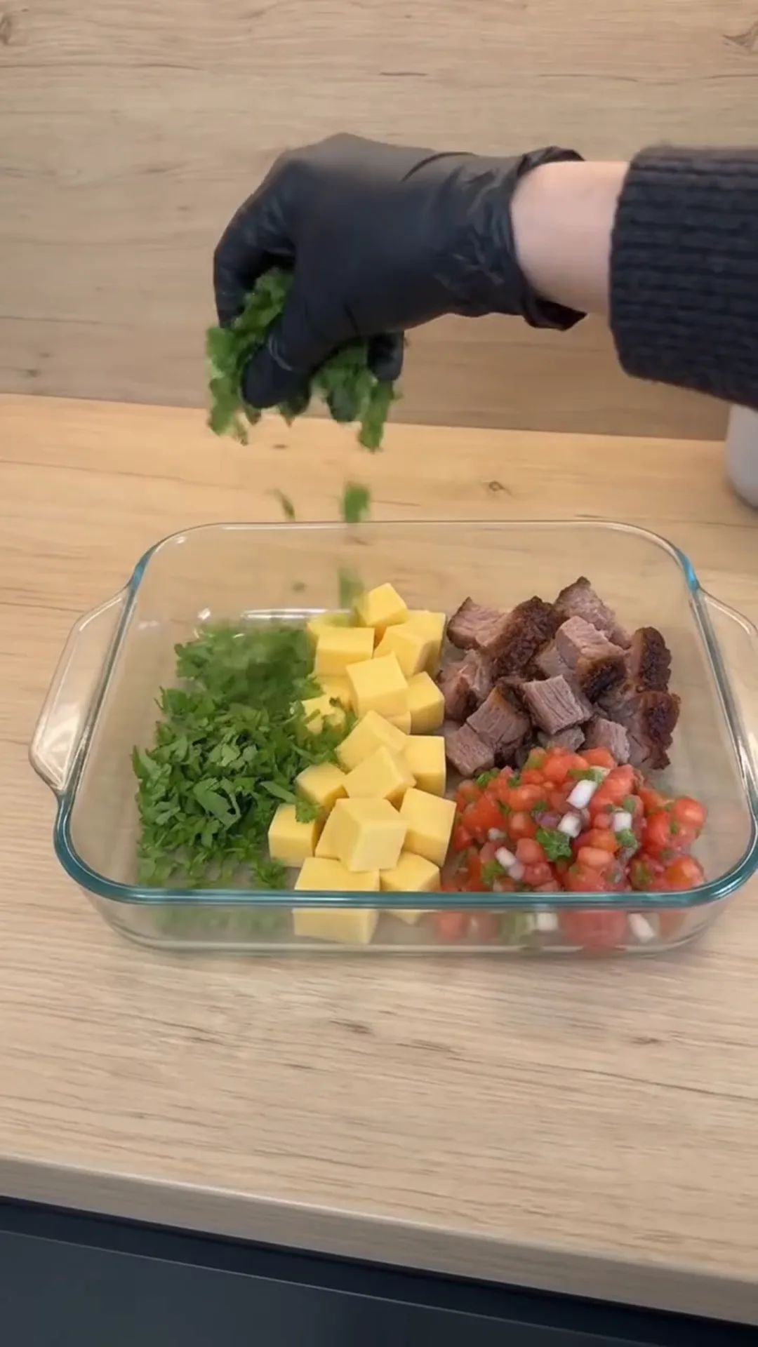 Creamy Smoked Brisket Queso Dip Recipe – person adding chopped green herbs to a salad