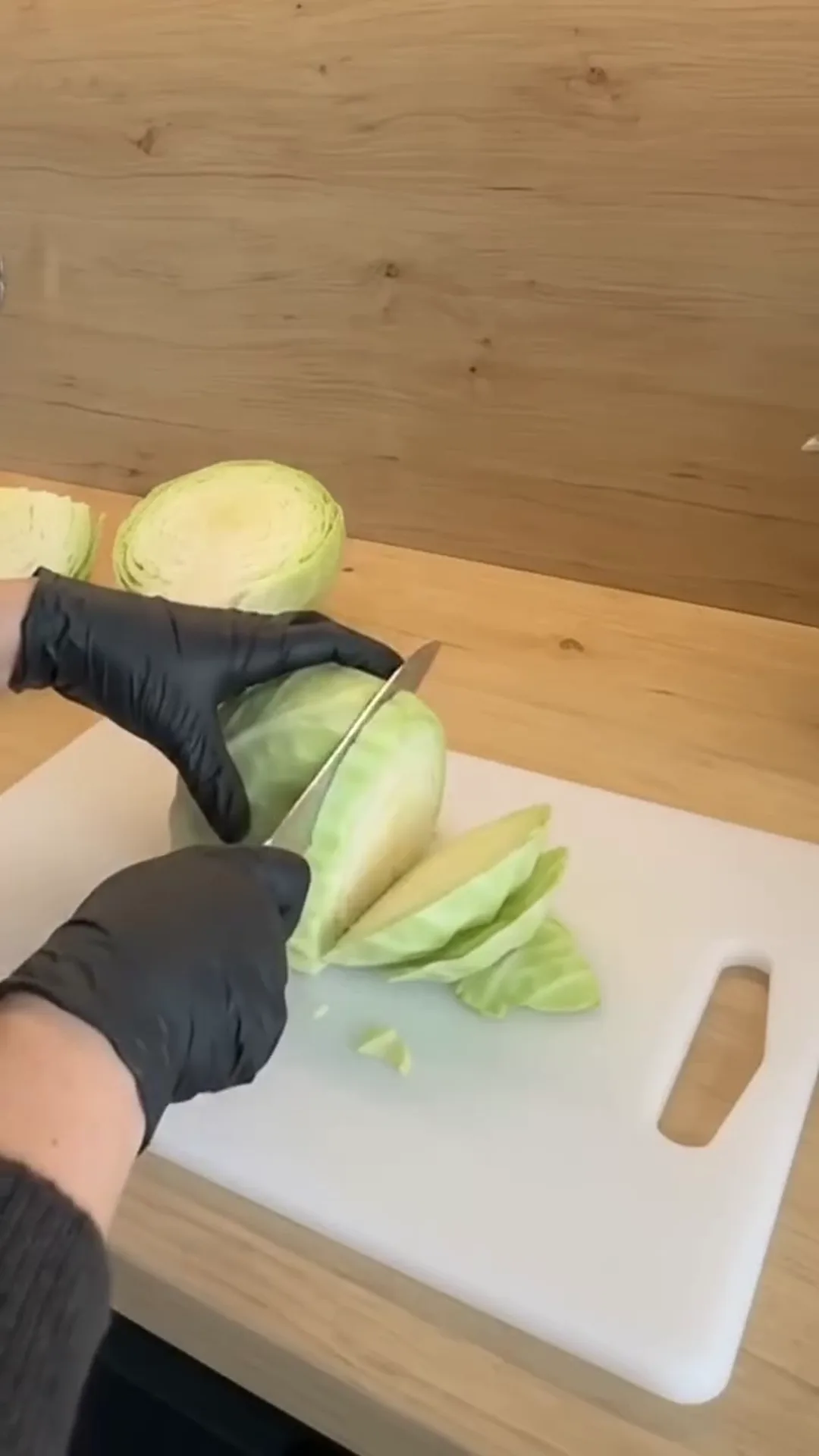 Creamy Sun-Dried Tomato Braised Cabbage Roasted Wedges – person cutting cabbage on a white cutting board