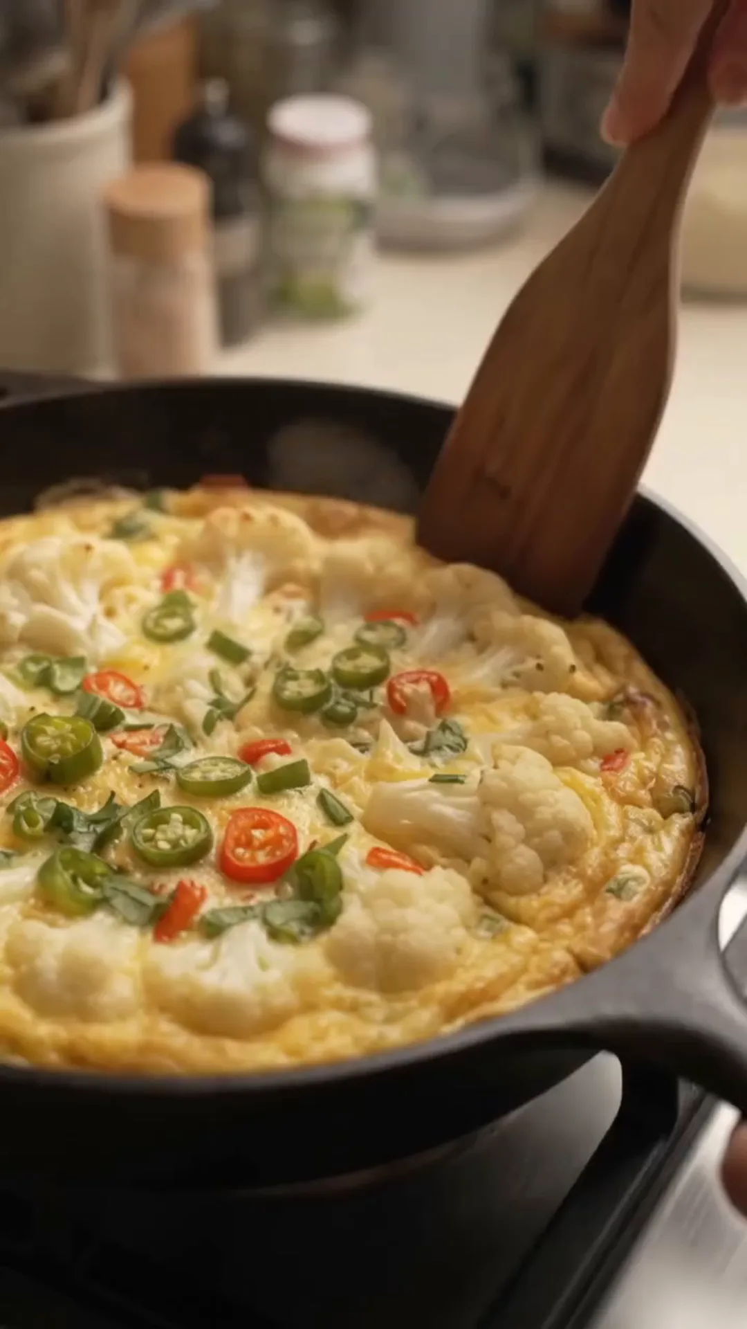 Crispy Cauliflower Chili Omelet Recipe – A hand is stirring a frittata in a pan