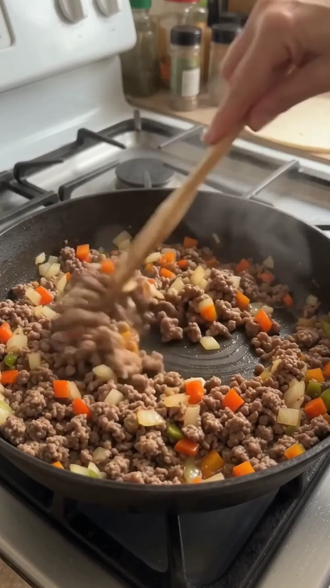 Crispy Cheesy Beef Tortilla Pockets Recipe – person stirring ground meat and vegetables in a pan