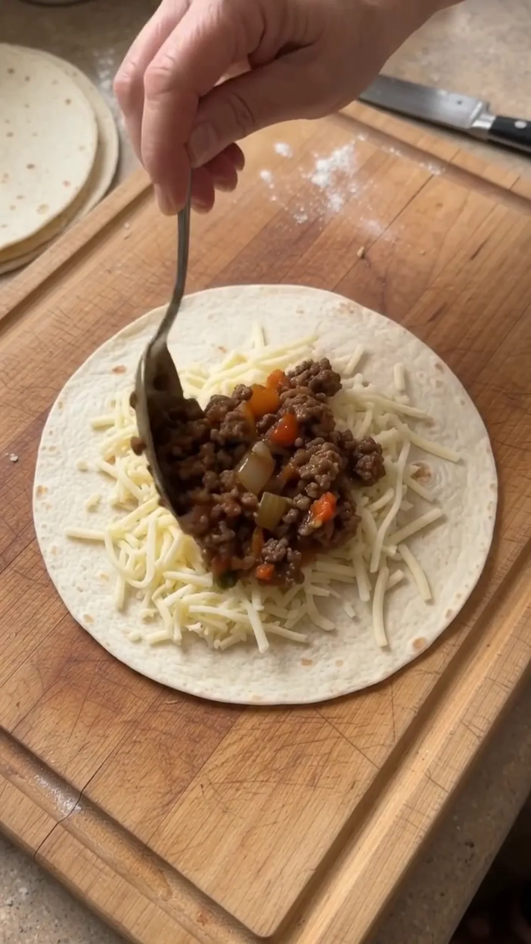 Crispy Cheesy Beef Tortilla Pockets Recipe – spooning ground beef and cheese onto a tortilla