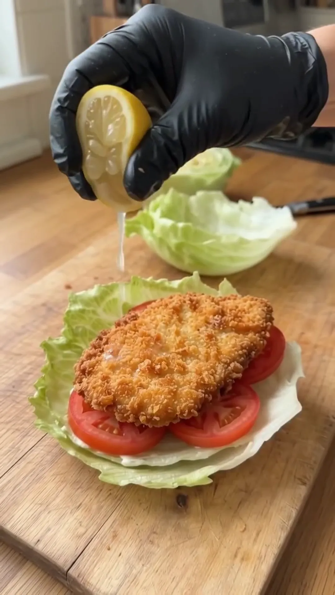 Crispy Chicken Lettuce Wraps with Avocado and Sauce – Squeezing lemon juice onto a breaded chicken sandwich