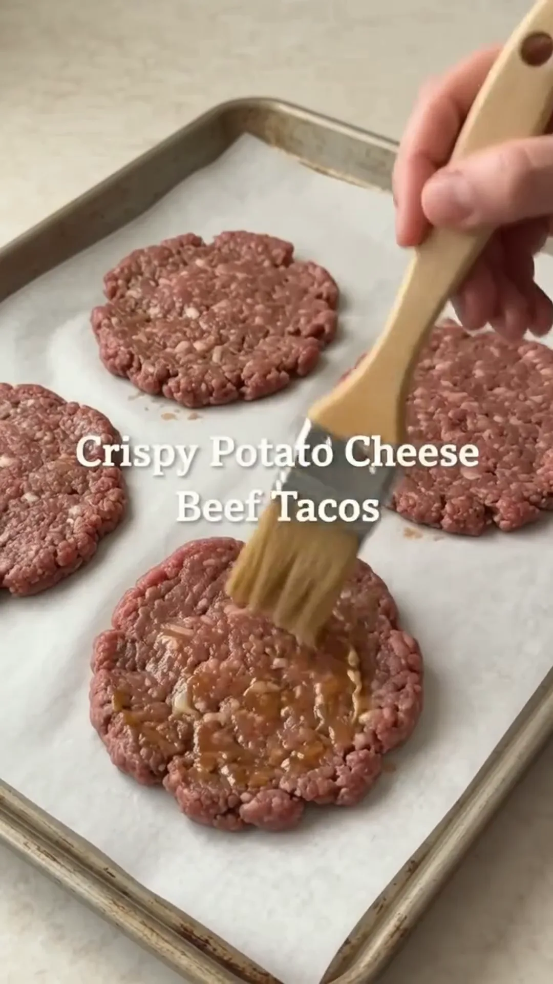 Crispy Potato Cheese Beef Tacos with Easy Sauce – beef patties being brushed with oil on a baking tray