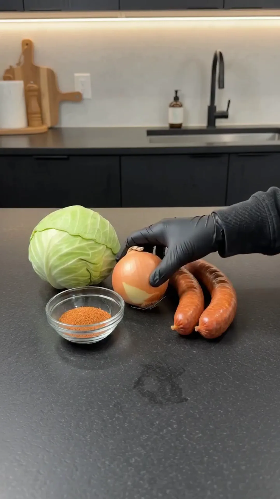 Easy Baked Cabbage and Smoked Beef Sausage Recipe – person is cutting an onion on a kitchen counter
