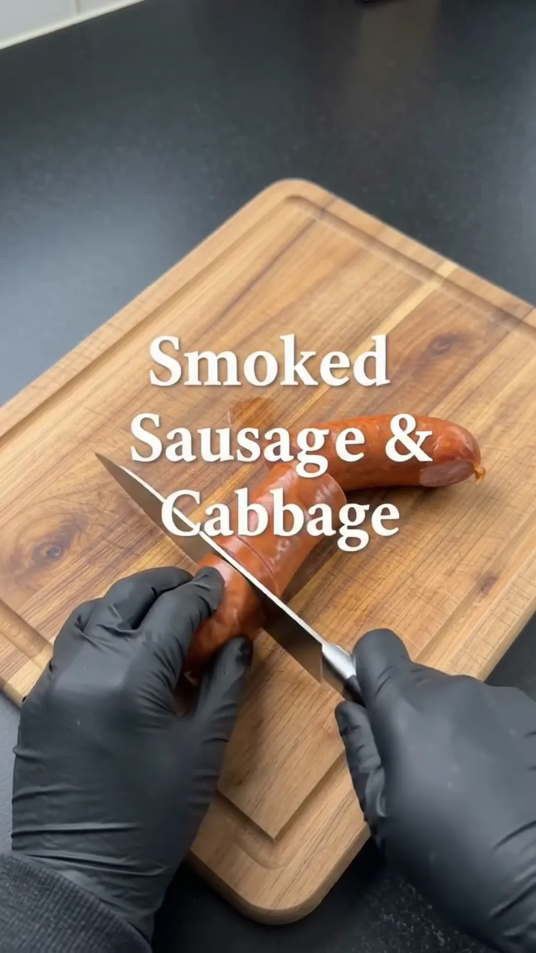Easy Baked Cabbage and Smoked Beef Sausage Recipe – Someone is cutting a sausage on a chopping board