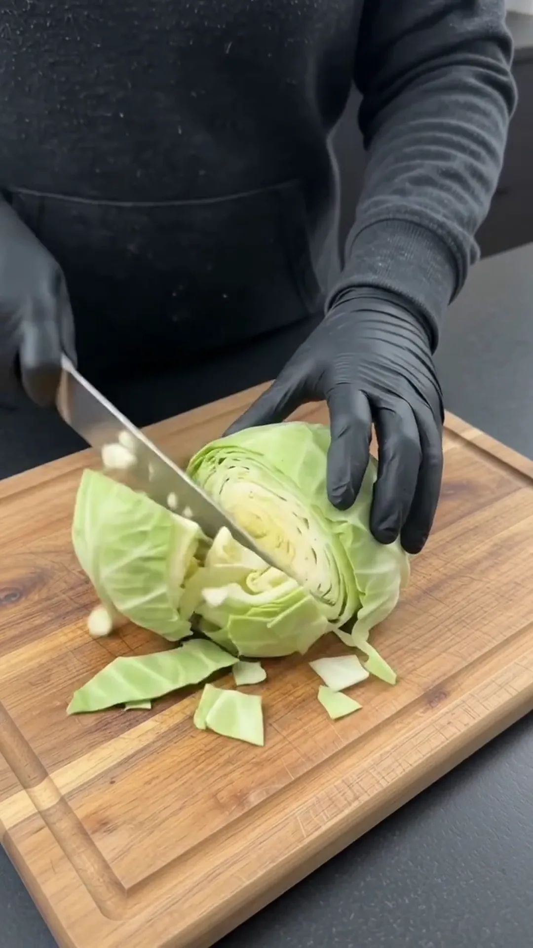 Easy Baked Cabbage and Smoked Beef Sausage Recipe – A person is cutting a head of cabbage on a wooden cutting board