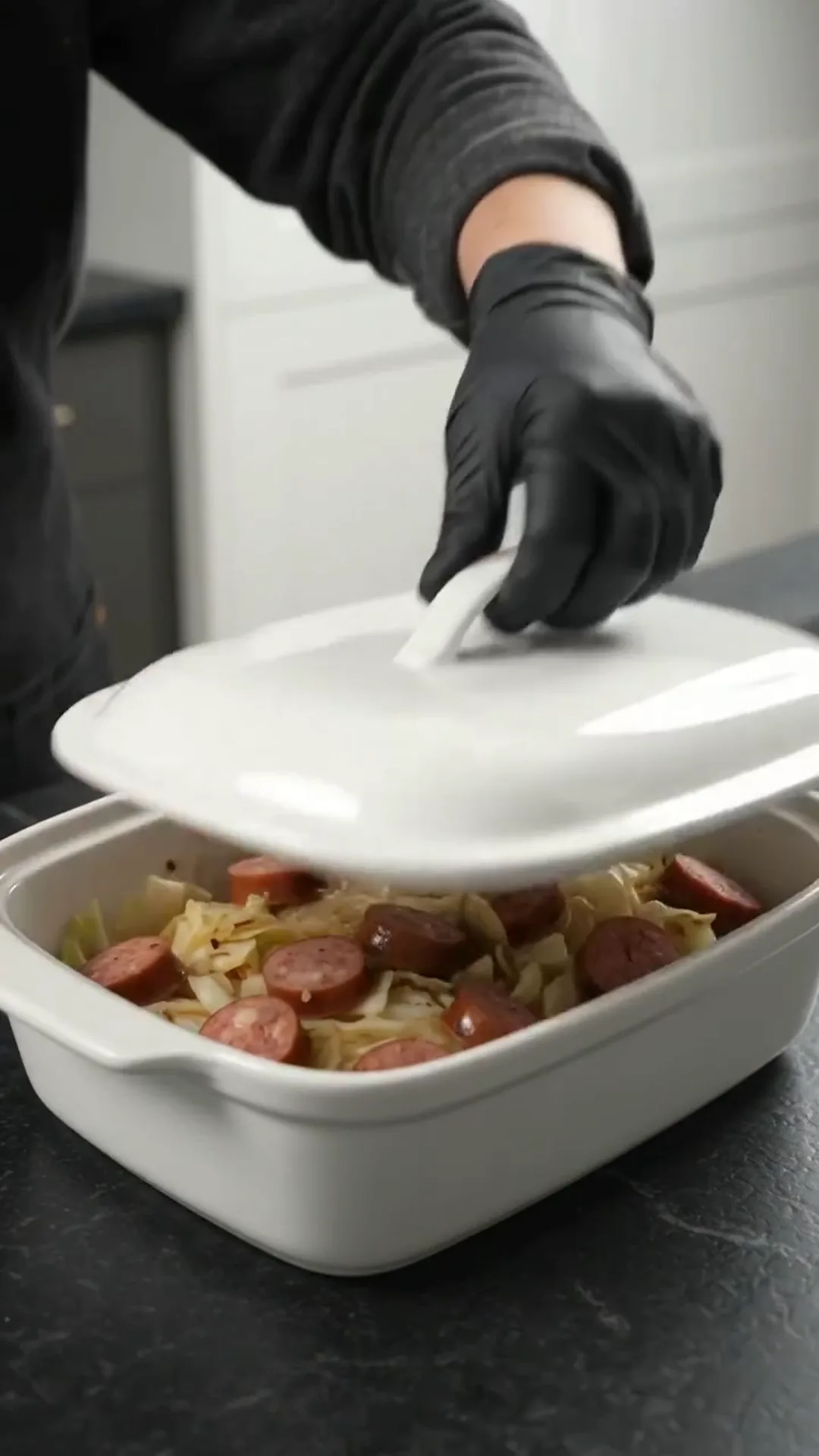 Easy Baked Cabbage and Smoked Beef Sausage Recipe – A person is putting a lid on a casserole dish