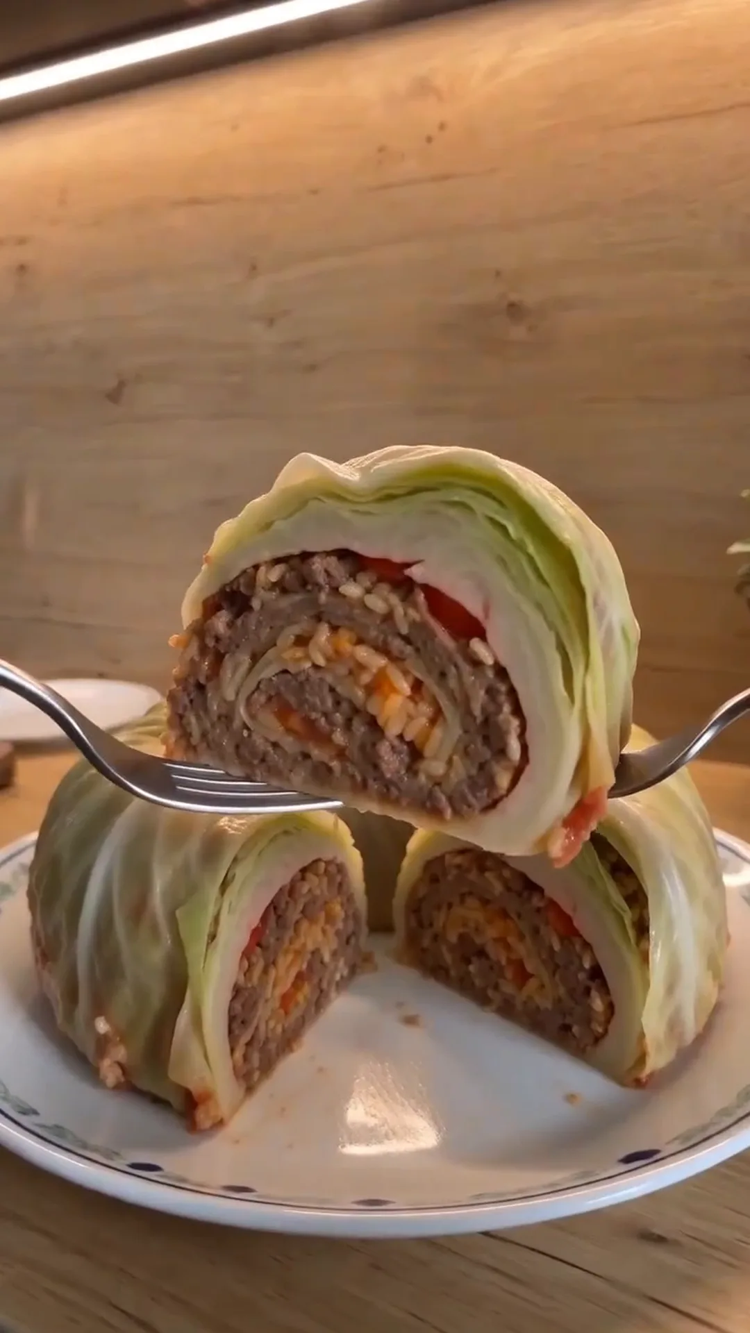 Easy Bundt Pan Cabbage Roll Ring with Beef and Rice – A person is cutting a cabbage-wrapped food item