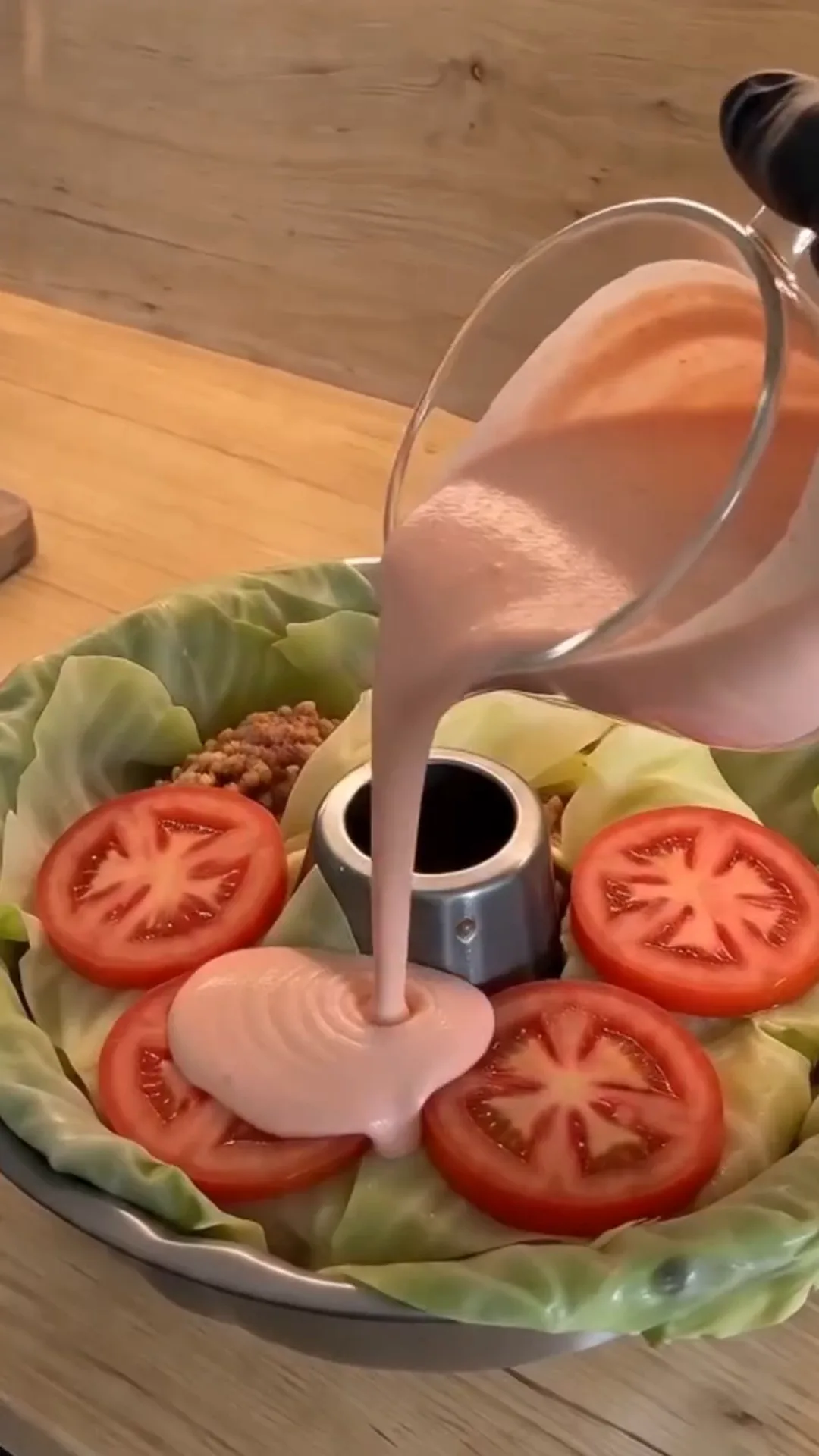 Easy Bundt Pan Cabbage Roll Ring with Beef and Rice – Pouring a pink sauce into a metal mold