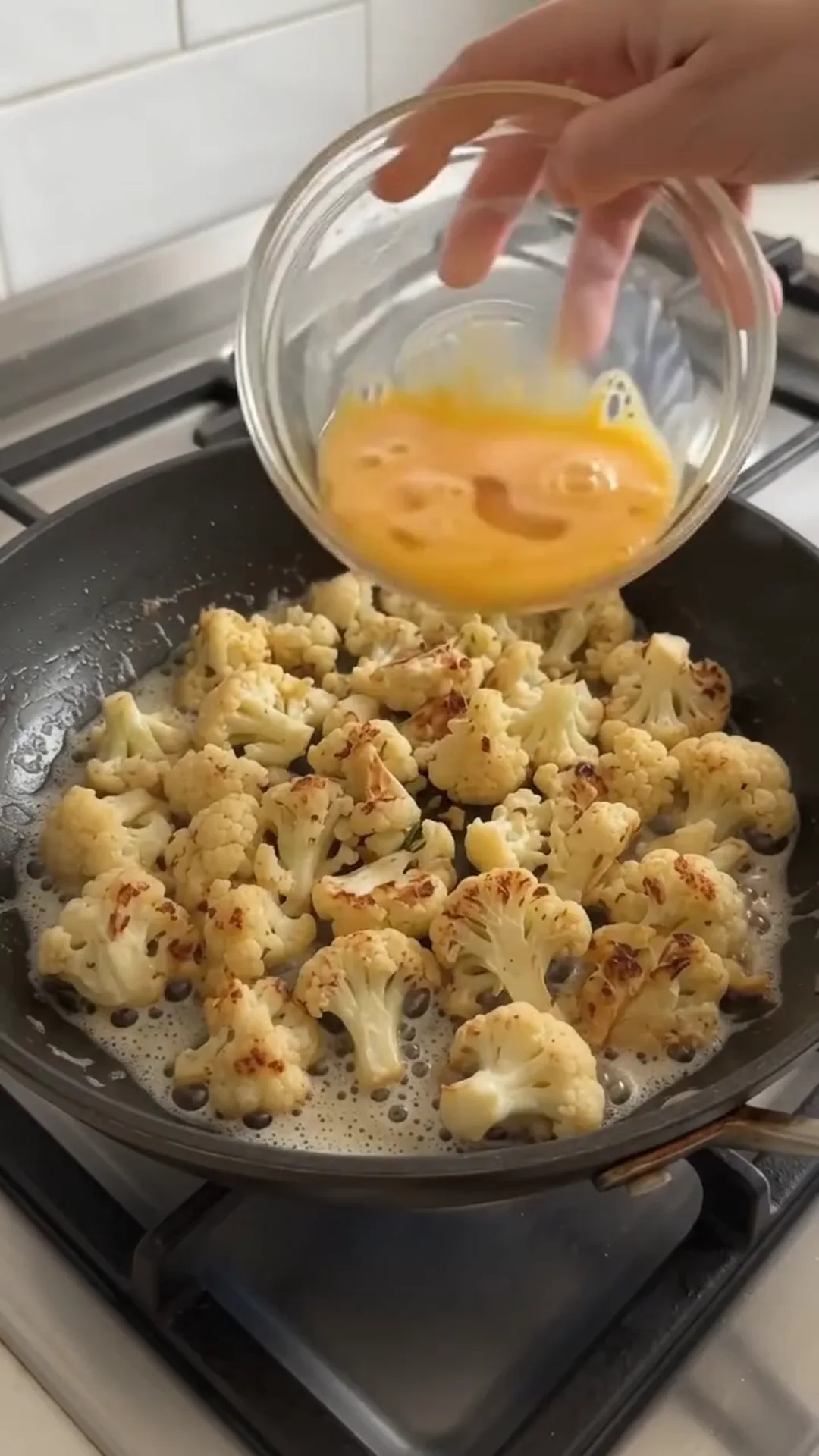Easy Pan Fried Cauliflower and Eggs with Fresh Dill – person is pouring egg mixture into a pan of cauliflower
