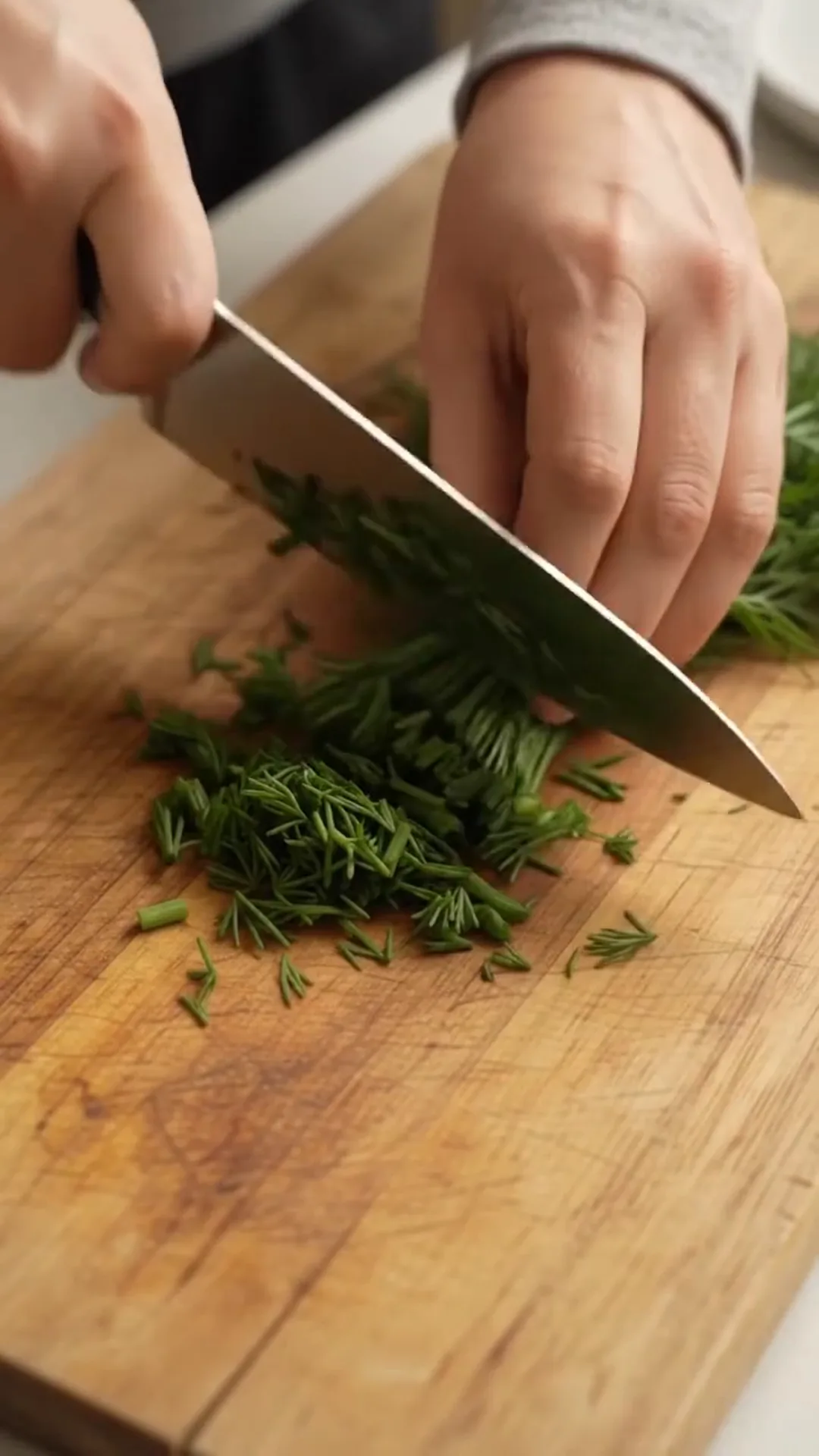 Easy Pan Fried Cauliflower and Eggs with Fresh Dill – A person is chopping herbs on a wooden cutting board