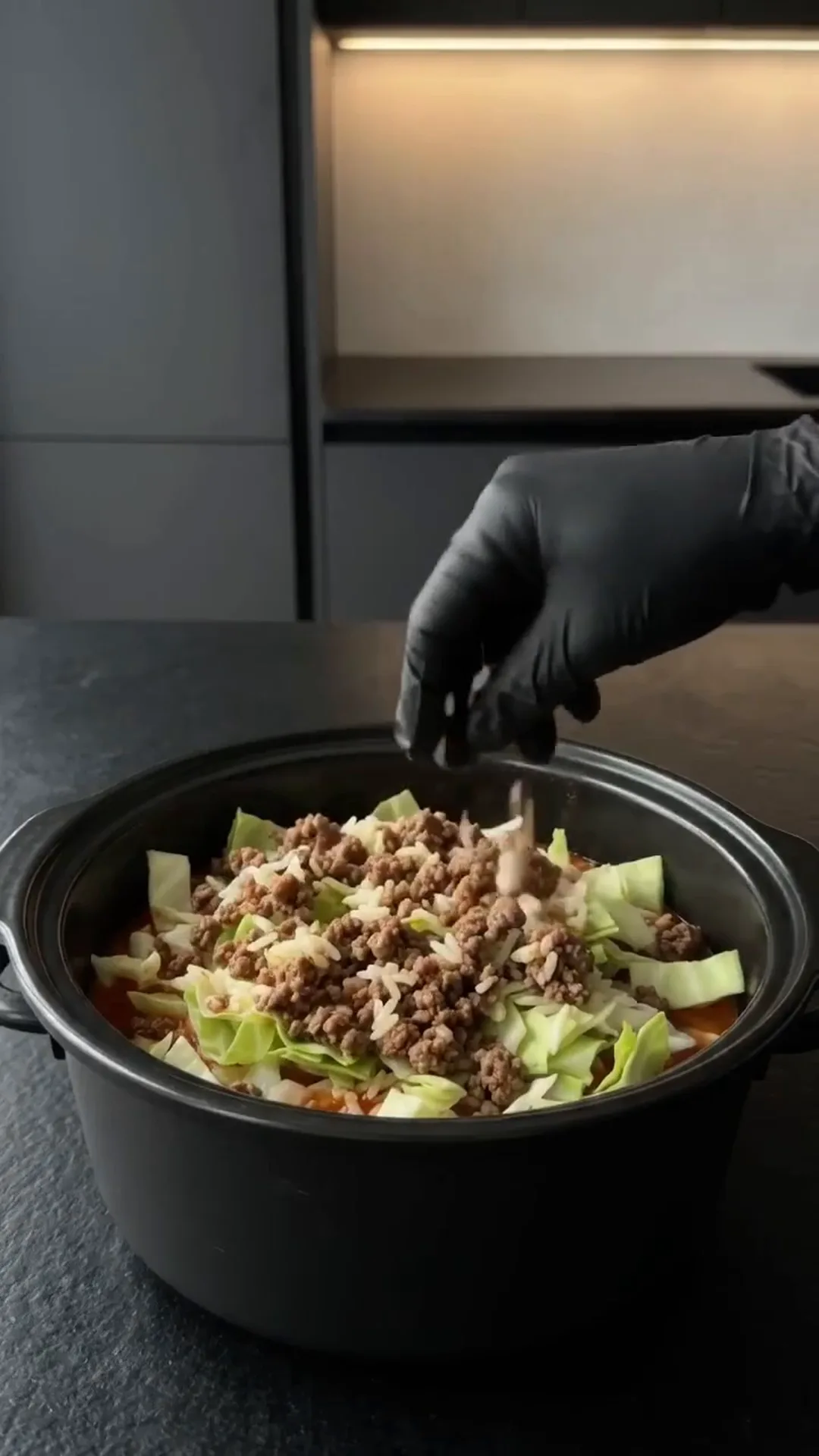 Easy slow cooker Cabbage Roll Casserole with Ground Beef – a hand is adding ingredients to a pot
