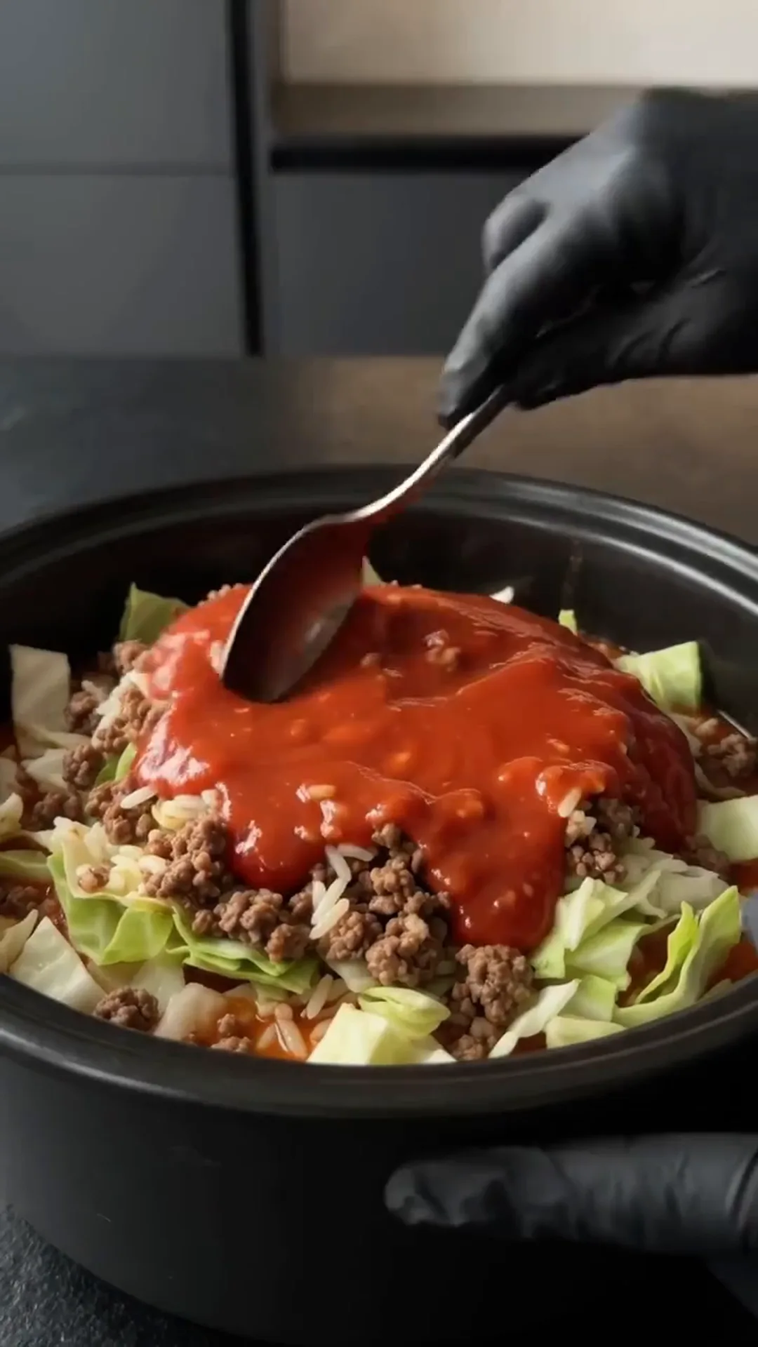Easy slow cooker Cabbage Roll Casserole with Ground Beef – adding a spoonful of red sauce to a crockpot