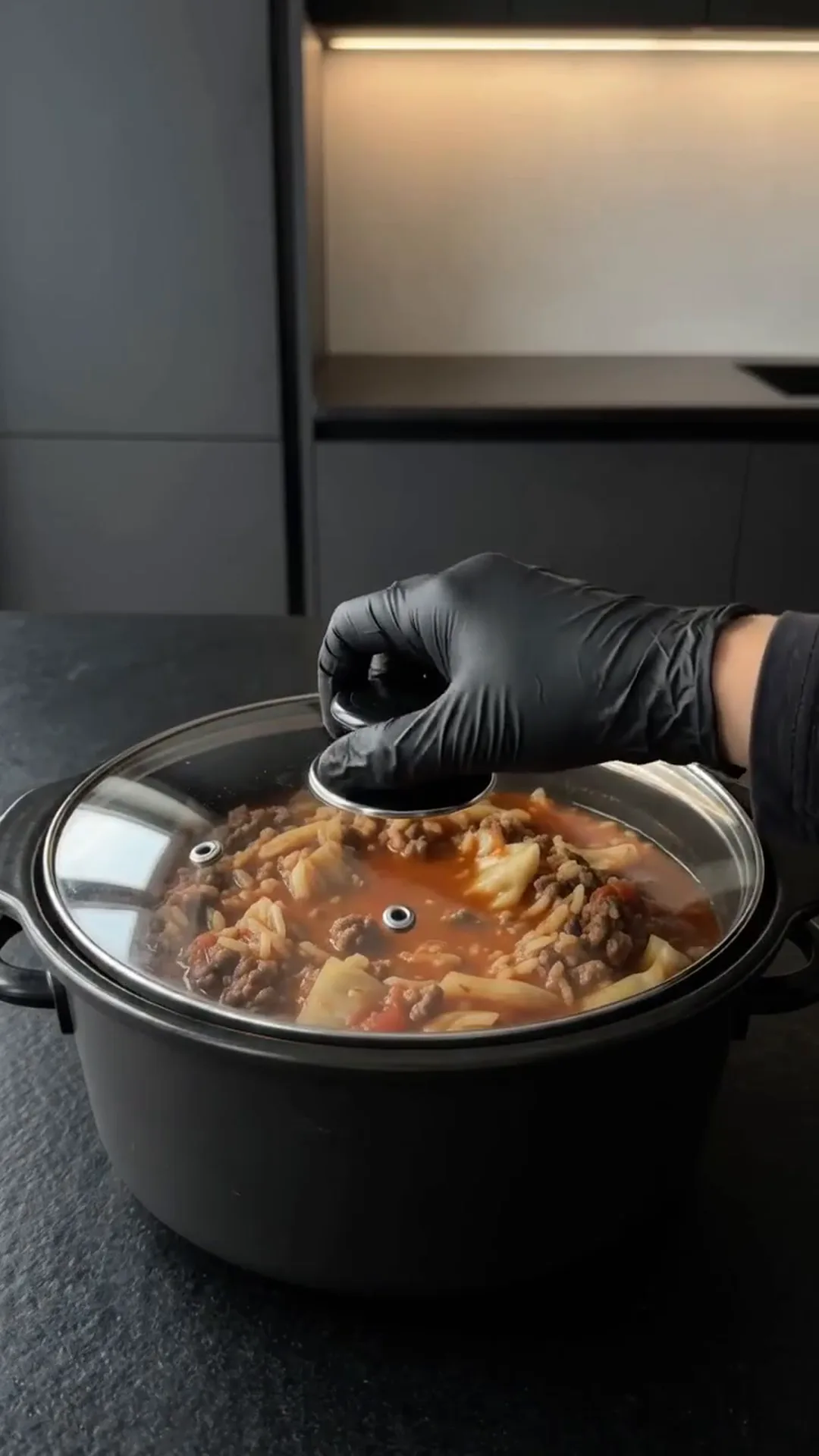 Easy slow cooker Cabbage Roll Casserole with Ground Beef – A hand is stirring a stew in a pot