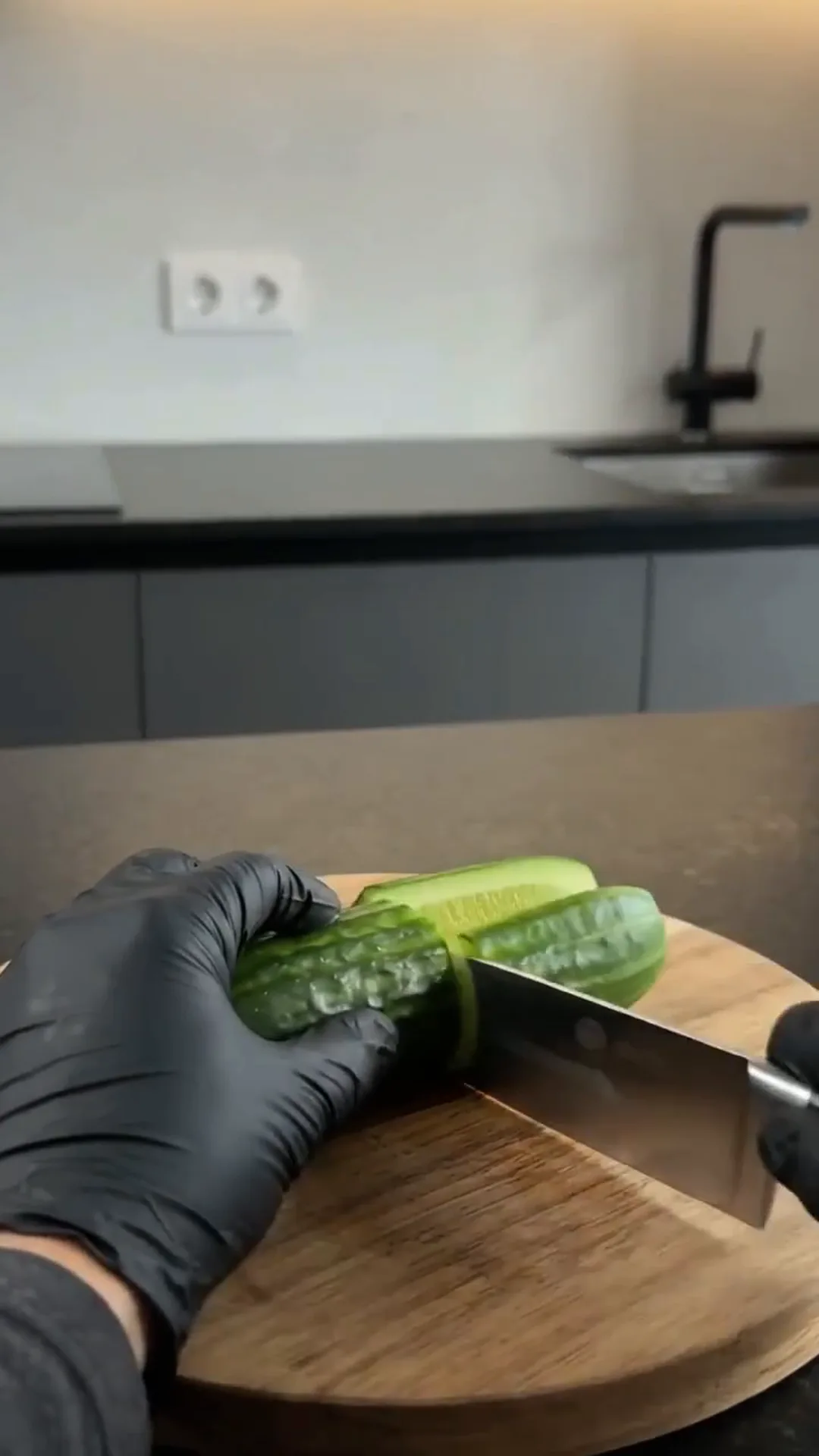 Easy Smoked Salmon Cucumber Sushi Boats – person cutting a cucumber on a wooden cutting board