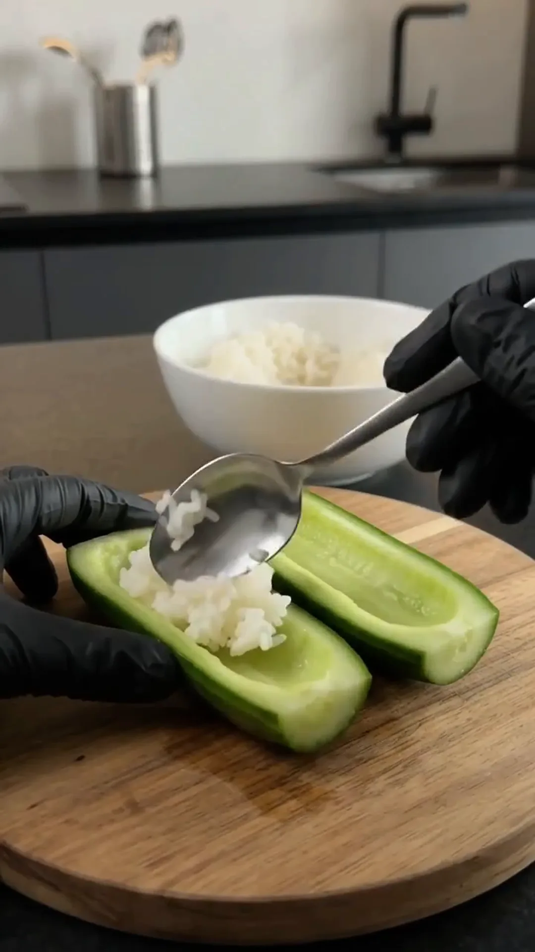 Easy Smoked Salmon Cucumber Sushi Boats – person is scooping rice into a cucumber