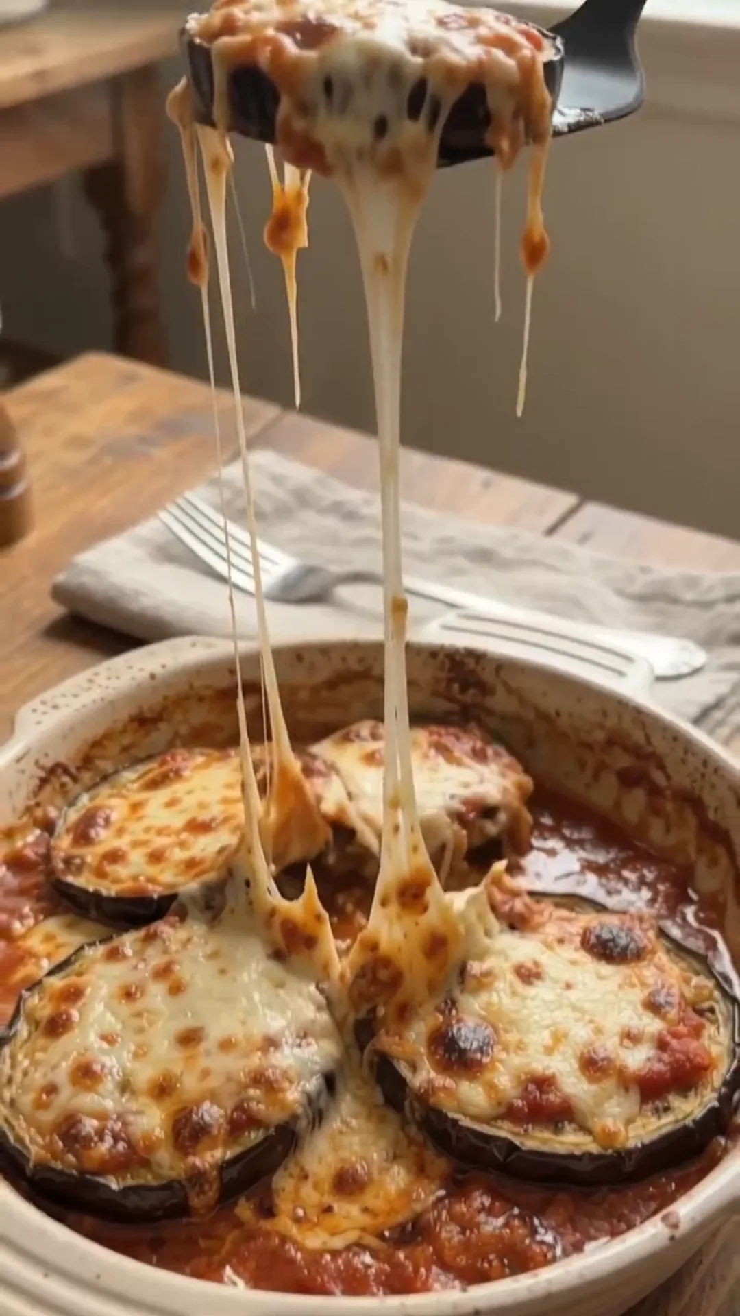 Easy Unbreaded Baked Eggplant Parmesan Recipe – pulling melted cheese from a dish of eggplant parmesan