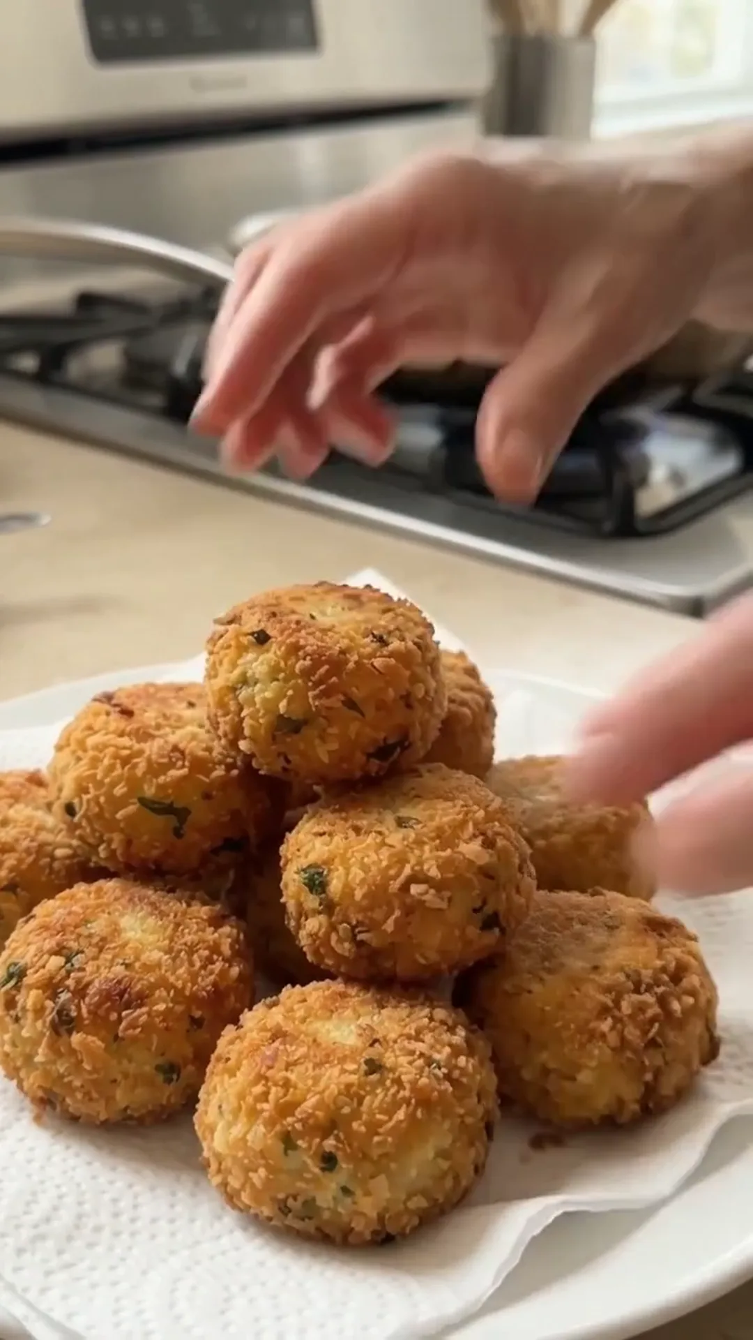 Golden Crispy Cheesy Potato Croquettes Recipe – A hand reaching for a plate of fried food