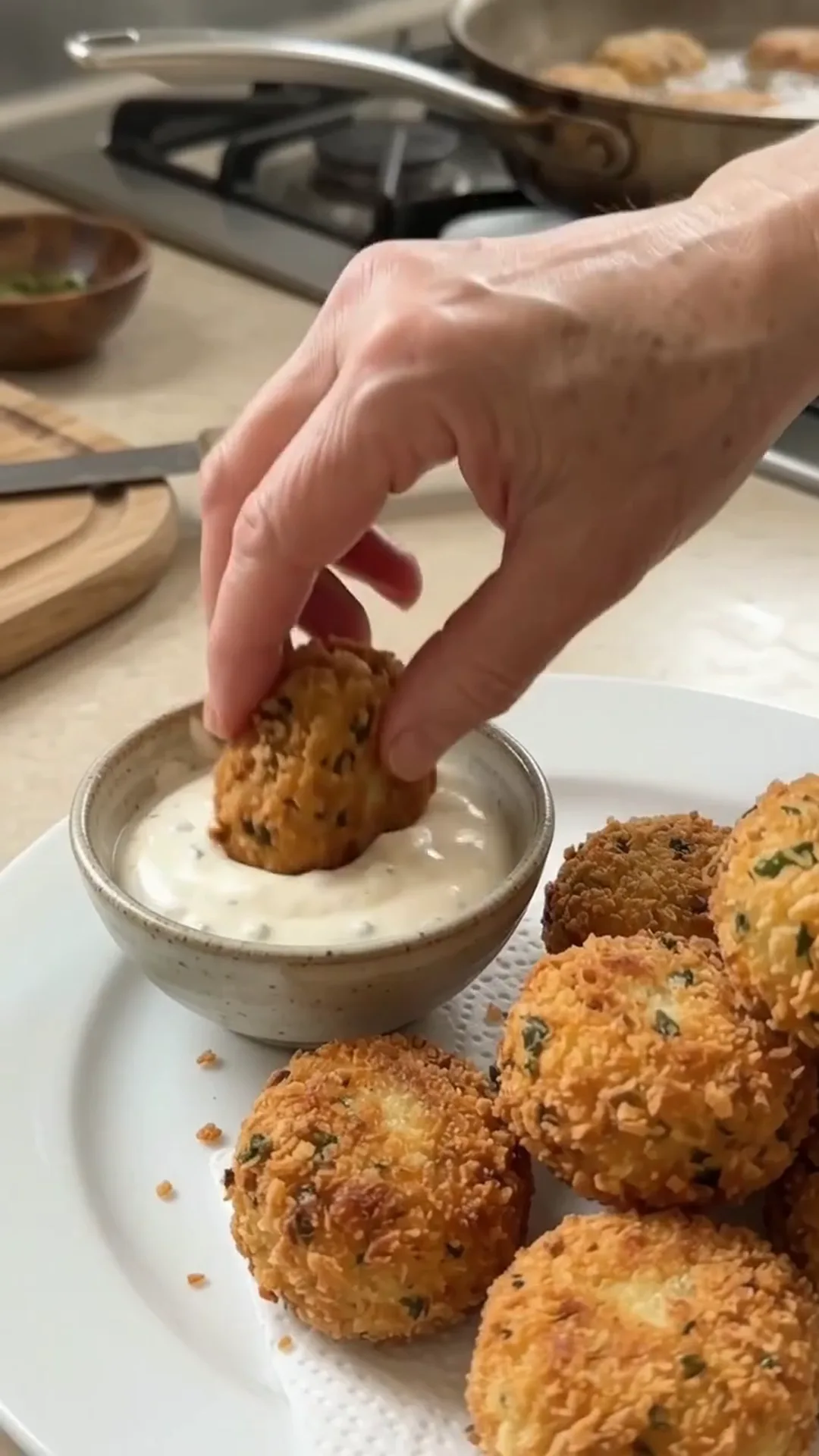 Golden Crispy Cheesy Potato Croquettes Recipe – A hand dipping a fried food item into a sauce