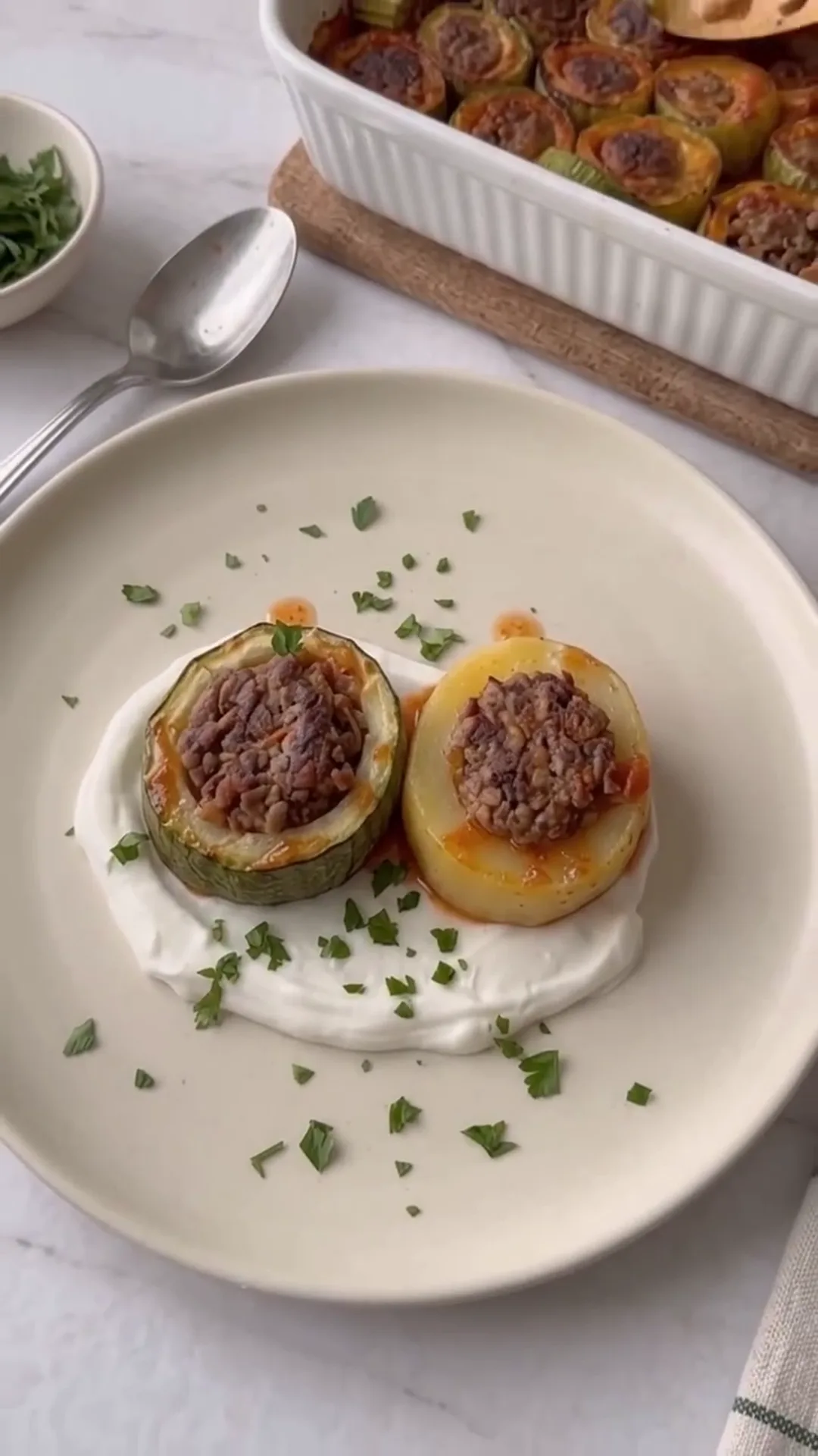 Hearty Meat-Stuffed Zucchini and Potato Bake – A dish is being plated, possibly stuffed zucchini