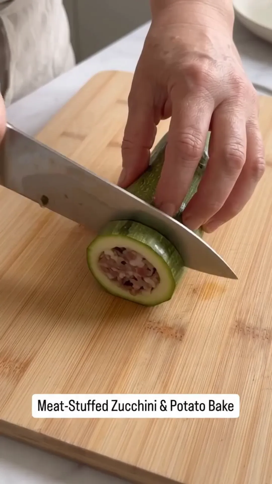 Hearty Meat-Stuffed Zucchini and Potato Bake – Someone is cutting a zucchini stuffed with meat and potatoes