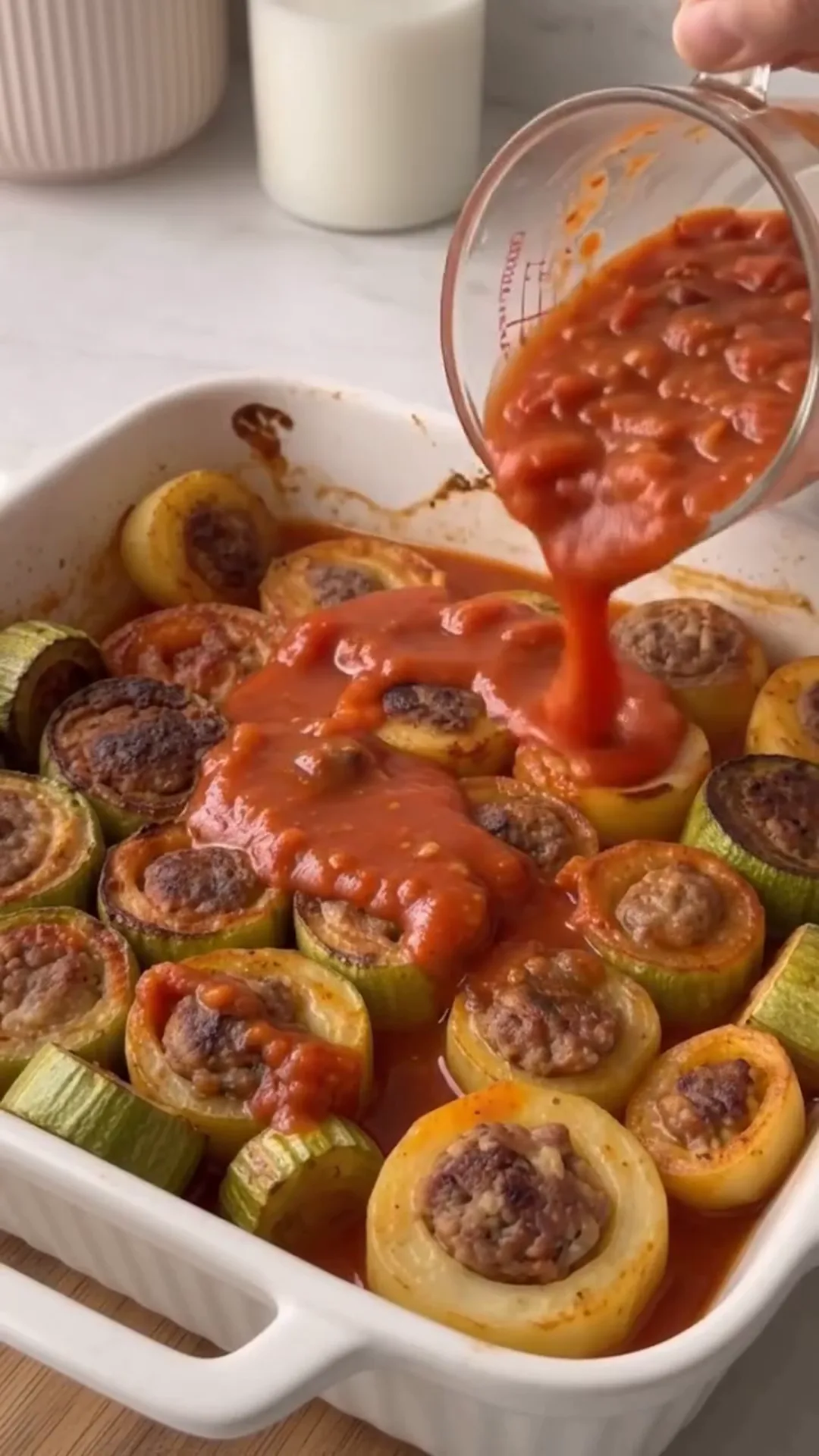 Hearty Meat-Stuffed Zucchini and Potato Bake – Pouring tomato sauce over stuffed zucchini rolls