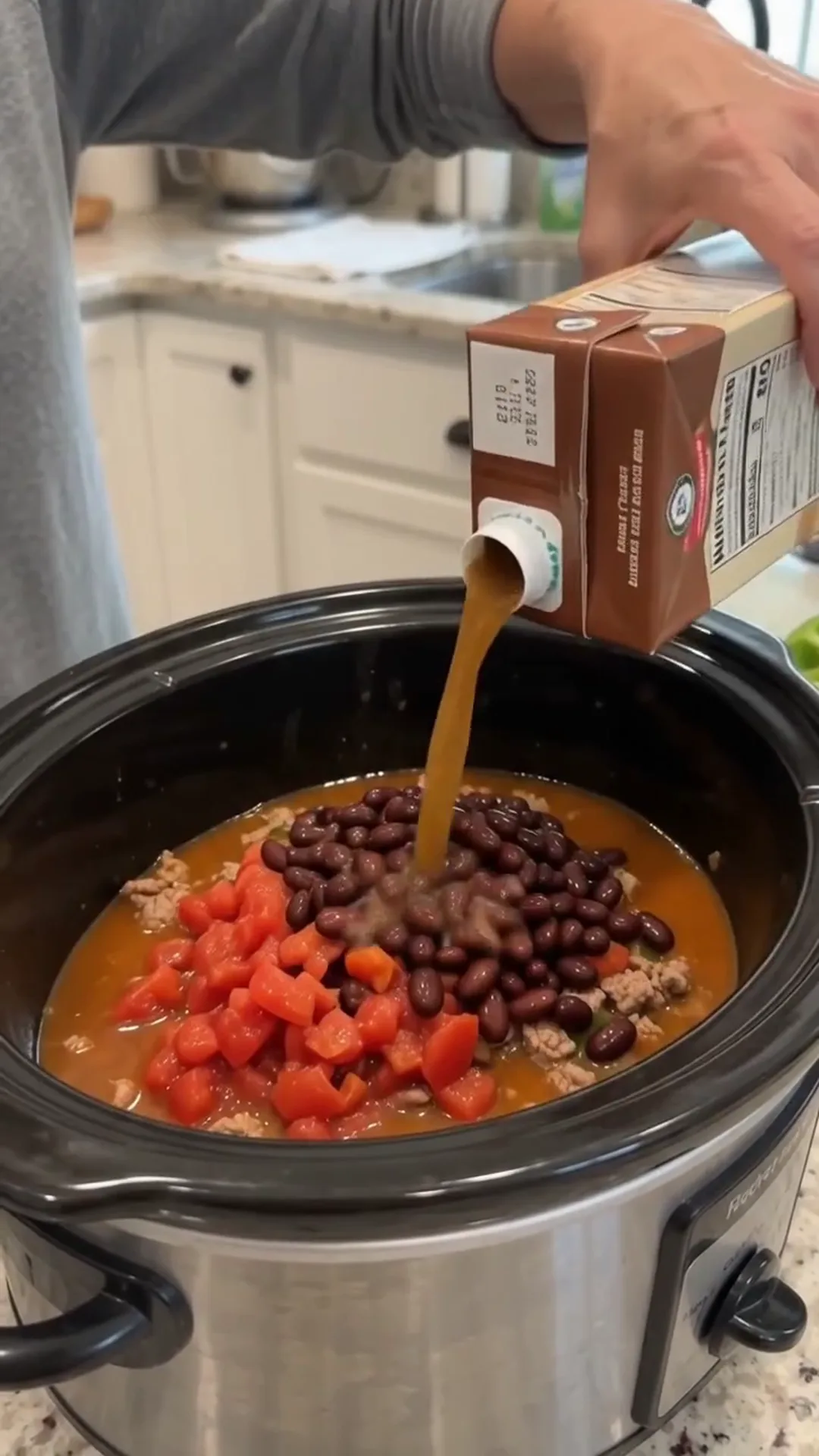 Hearty Slow Cooker Beef and Turkey Chili Recipe – Pouring liquid into a slow cooker with ingredients