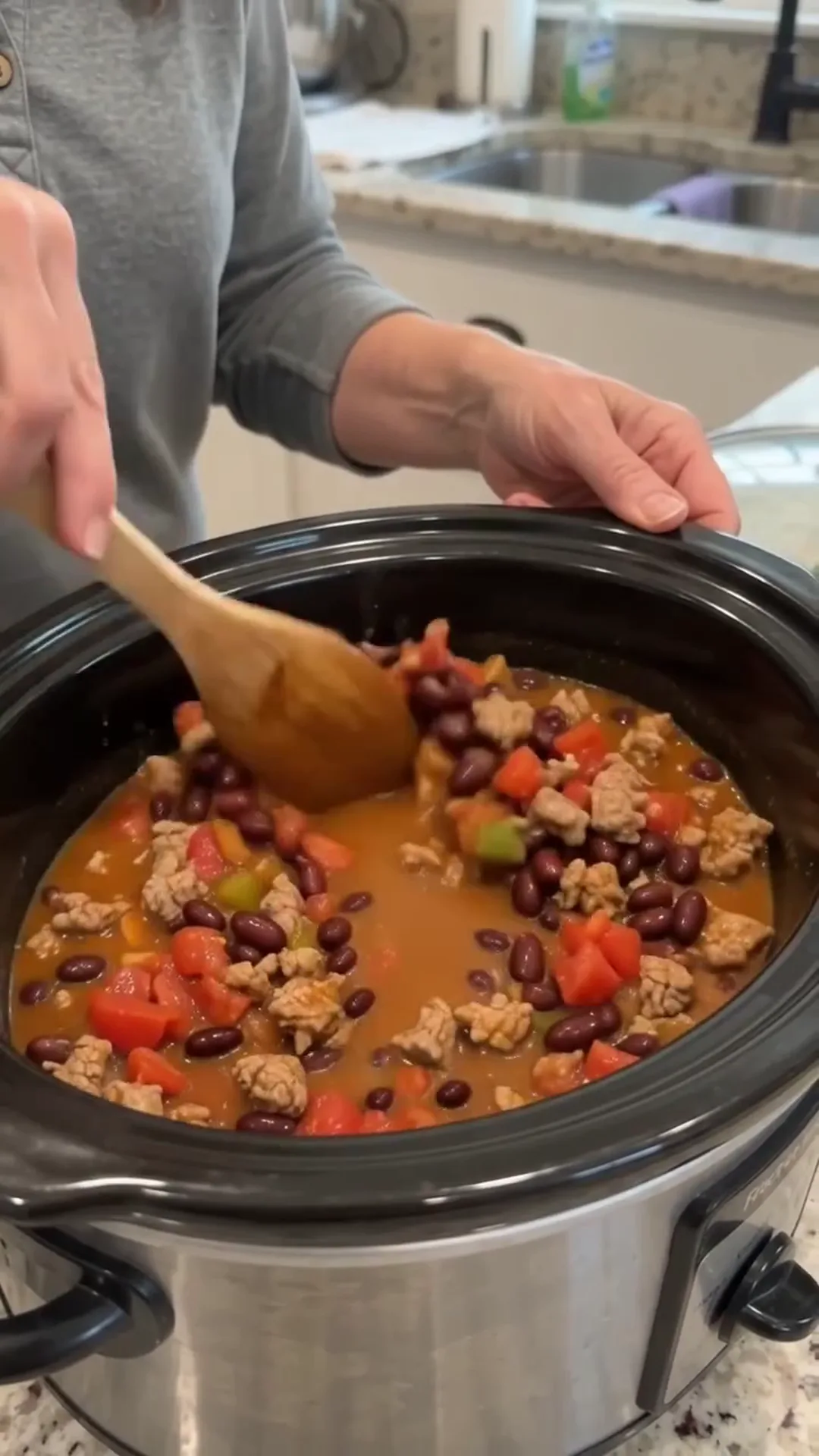 Hearty Slow Cooker Beef and Turkey Chili Recipe – person stirring a crockpot of food
