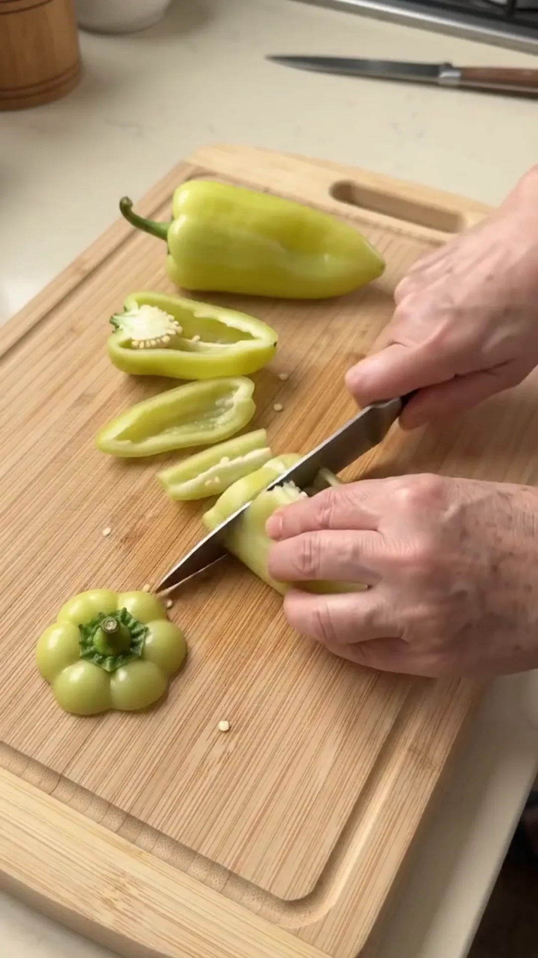 Hearty Stuffed Peppers with Beef and Rice over Mashed Potatoes – A person is cutting a pepper on a wooden cutting board