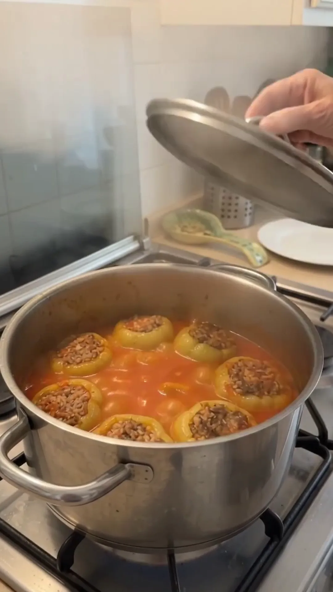 Hearty Stuffed Peppers with Beef and Rice over Mashed Potatoes – Someone is cooking stuffed peppers in a pot on a stove