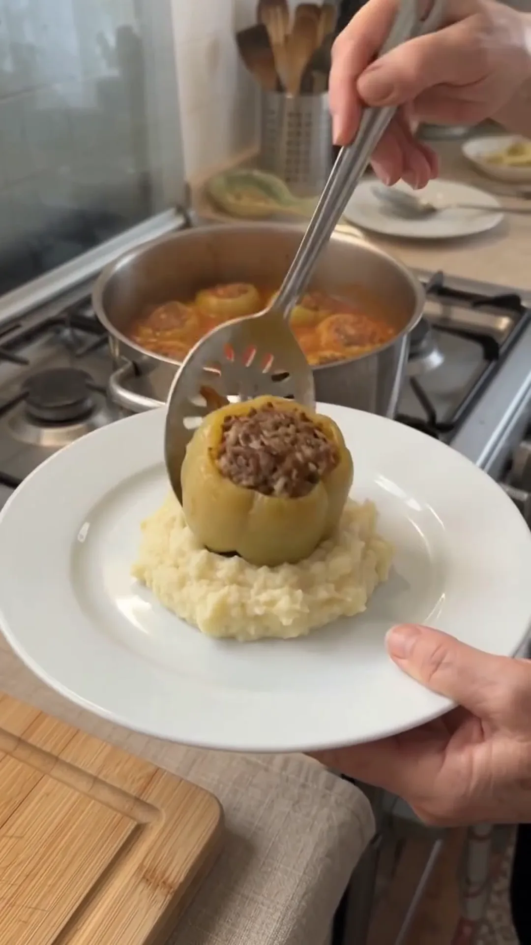 Hearty Stuffed Peppers with Beef and Rice over Mashed Potatoes – A person is serving a stuffed pepper on a plate