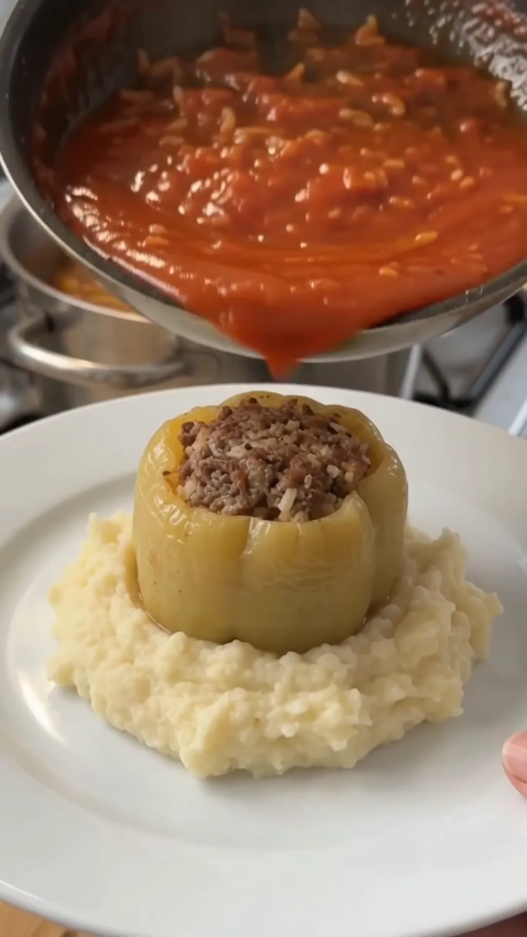 Hearty Stuffed Peppers with Beef and Rice over Mashed Potatoes – Pouring tomato sauce into a stuffed pepper