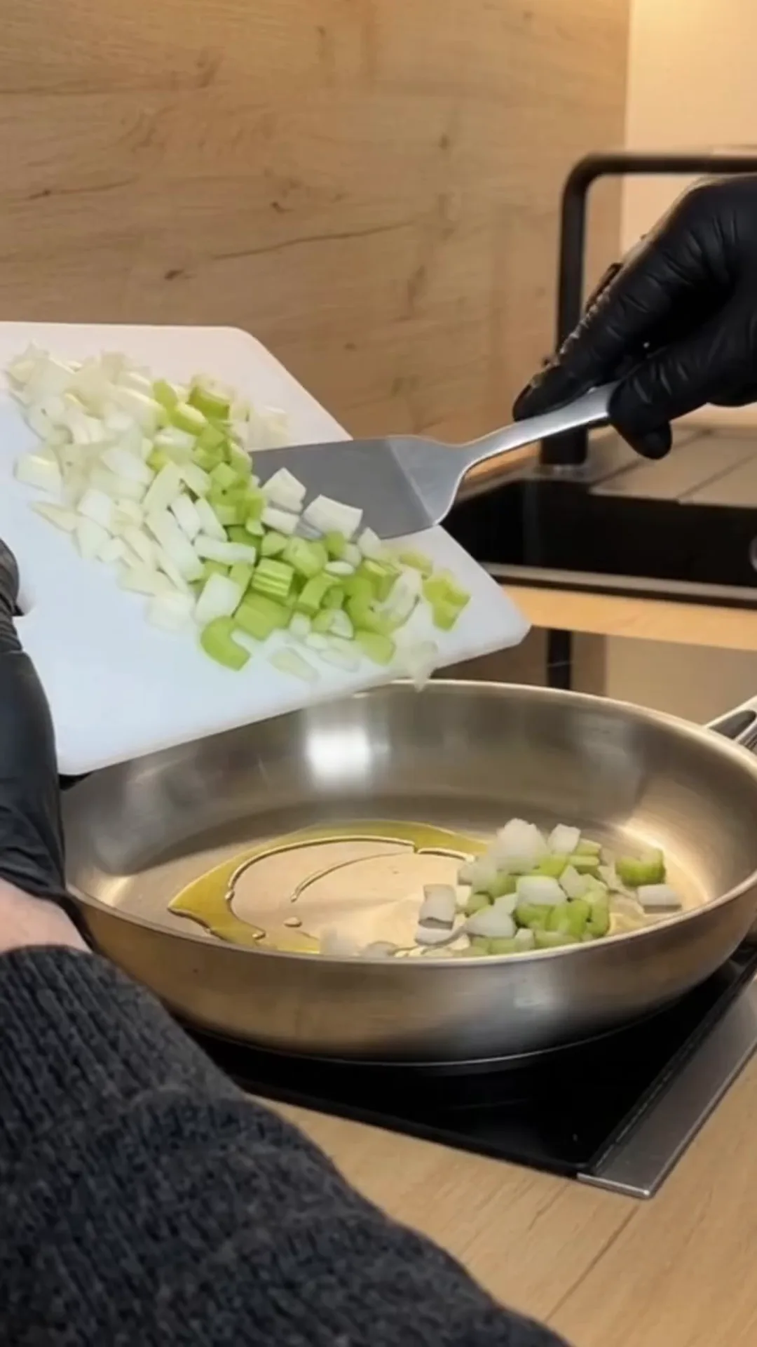 Hearty Turkey and Dumplings Soup with Herb Broth – person chopping celery and onions in a pan