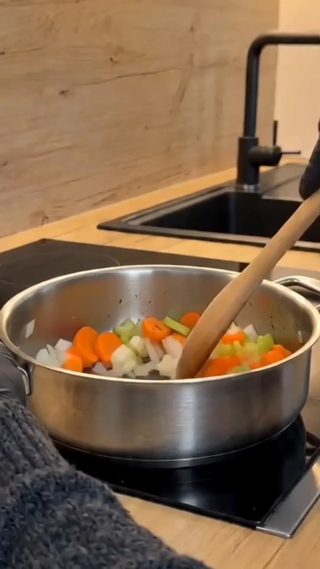 Hearty Turkey and Dumplings Soup with Herb Broth – Someone is stirring a pot of vegetables on a stovetop