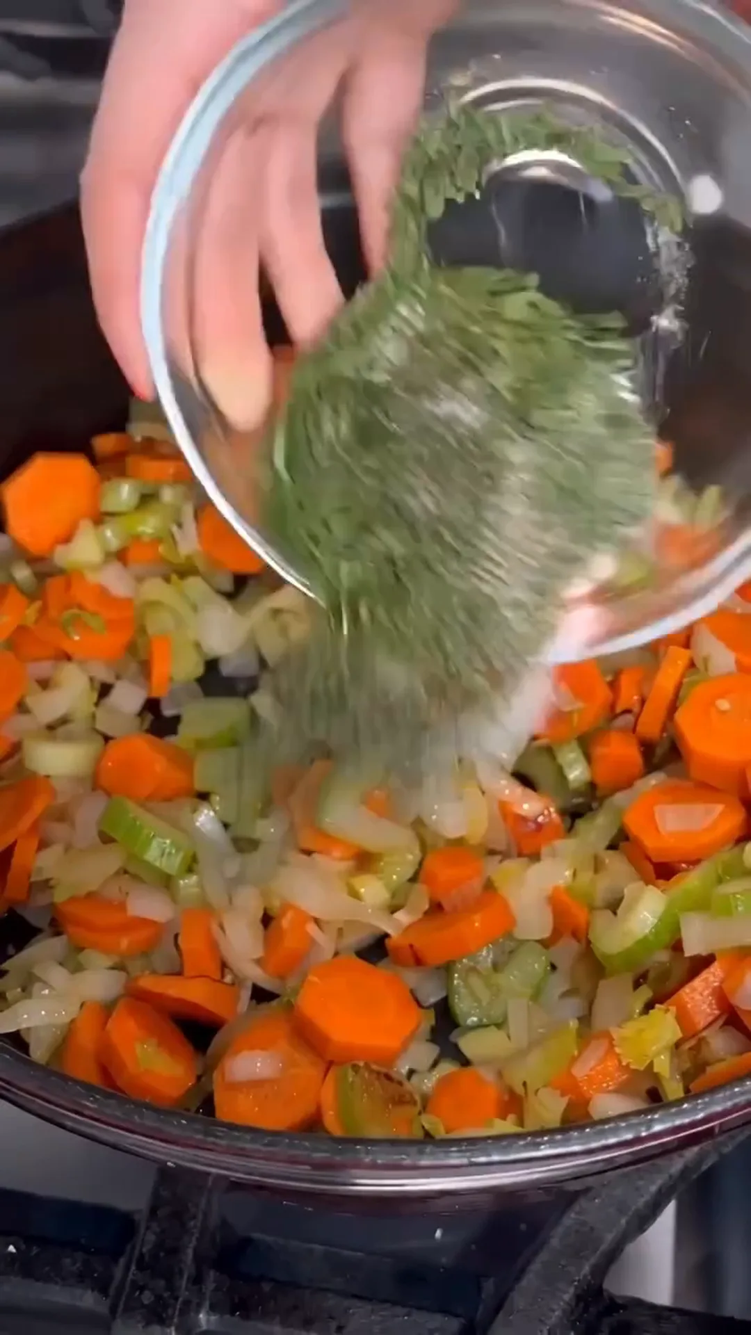 Hearty Turkey and Dumplings Soup with Herb Broth – Pouring chopped vegetables into a pan