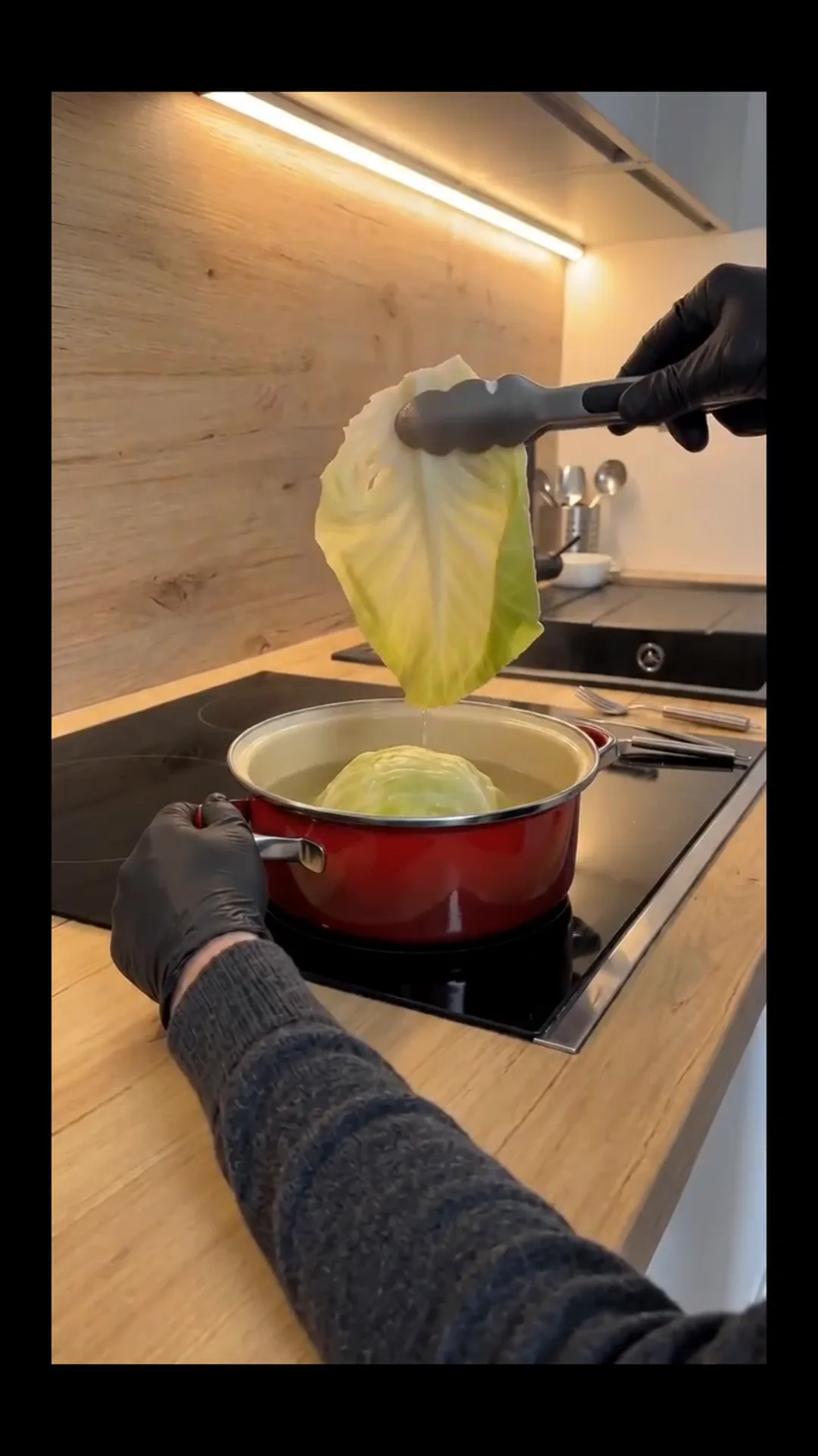 Hearty Vegan Stuffed Cabbage Rolls with Rice and Mushrooms – person cooking cabbage in a pot on a stove