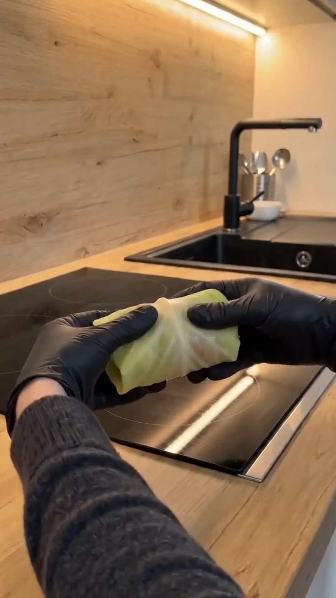 Hearty Vegan Stuffed Cabbage Rolls with Rice and Mushrooms – person wearing gloves holding a cabbage leaf
