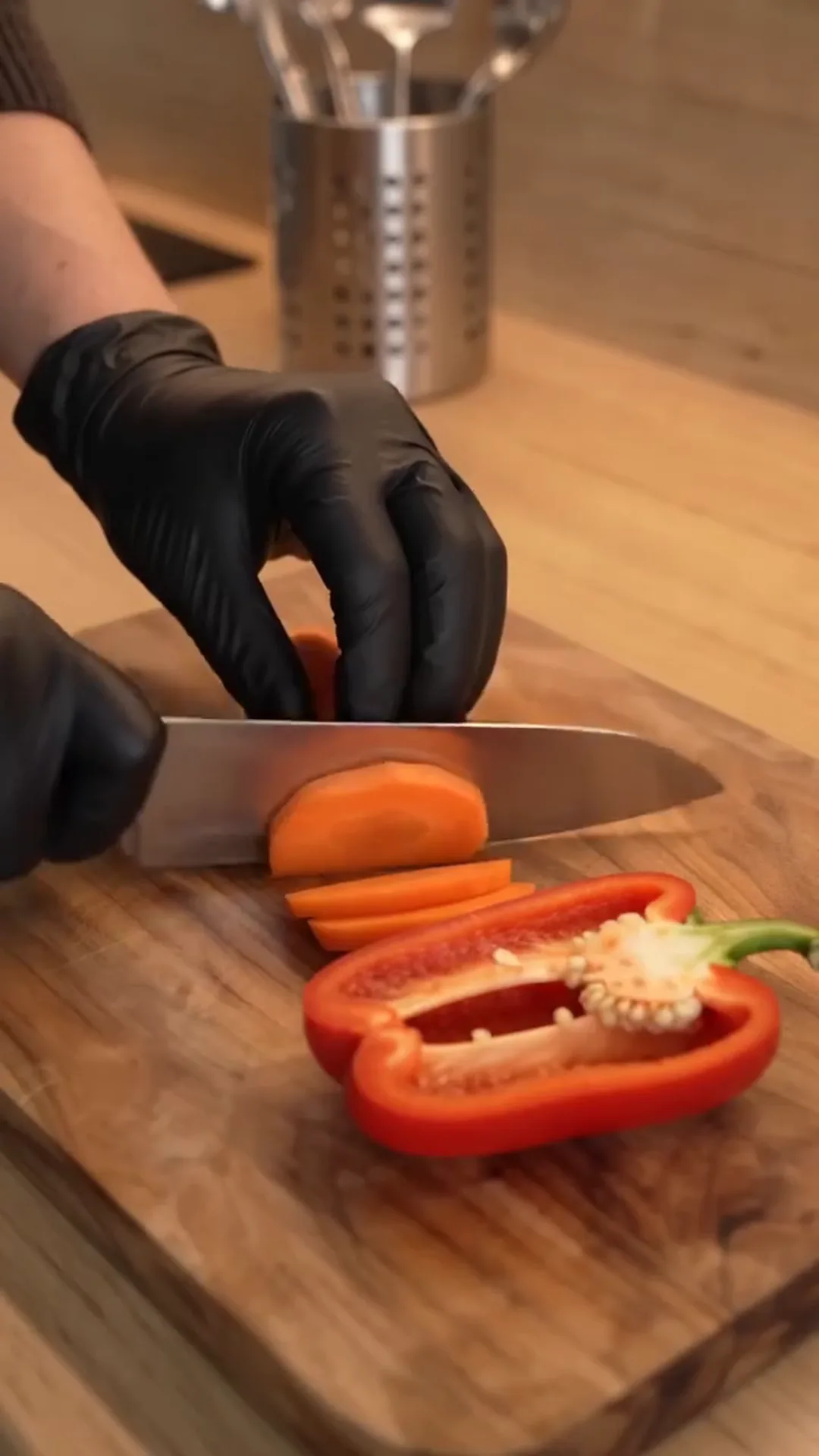 Herb-Roasted Mediterranean Vegetables with Garlic Yogurt – A person is cutting a red pepper on a wooden cutting board