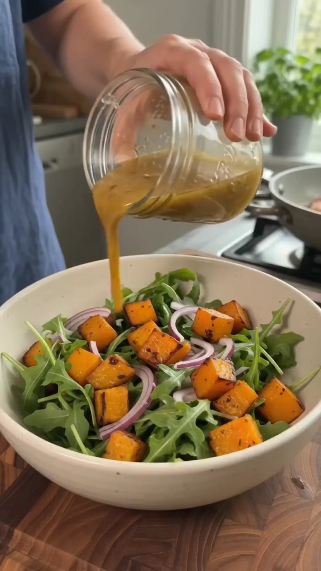 Honey-Glazed Salmon and Roasted Pumpkin Salad – Pouring salad dressing into a bowl of greens and vegetables