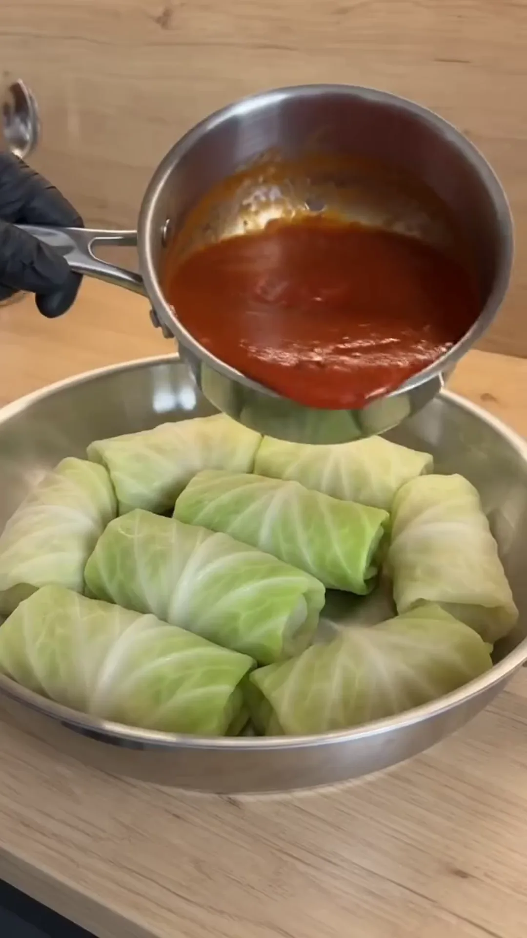 Individual Stuffed Cabbage Rolls with Ground Beef and Rice – Pouring tomato sauce into a bowl of cabbage rolls