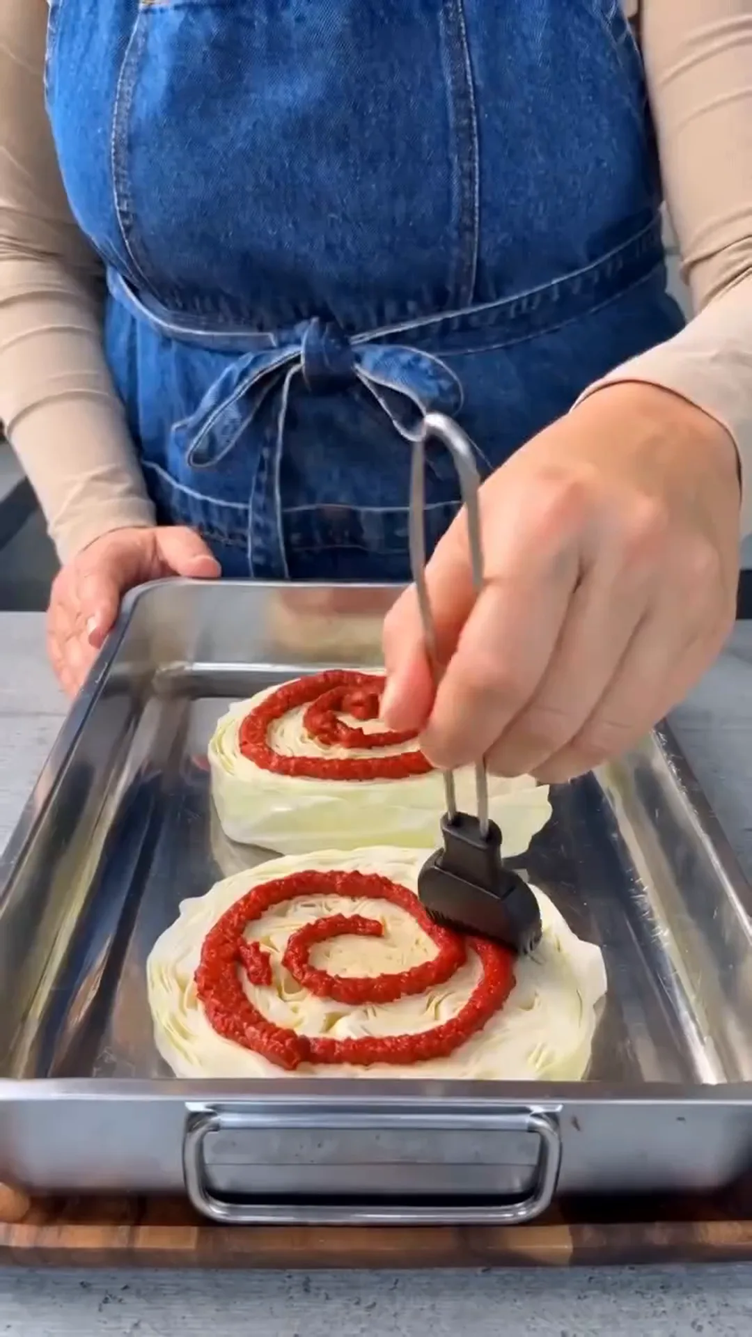 Italian Unrolled Cabbage Rolls with Creamy Tomato Sauce – applying red sauce to a pastry in a baking tray